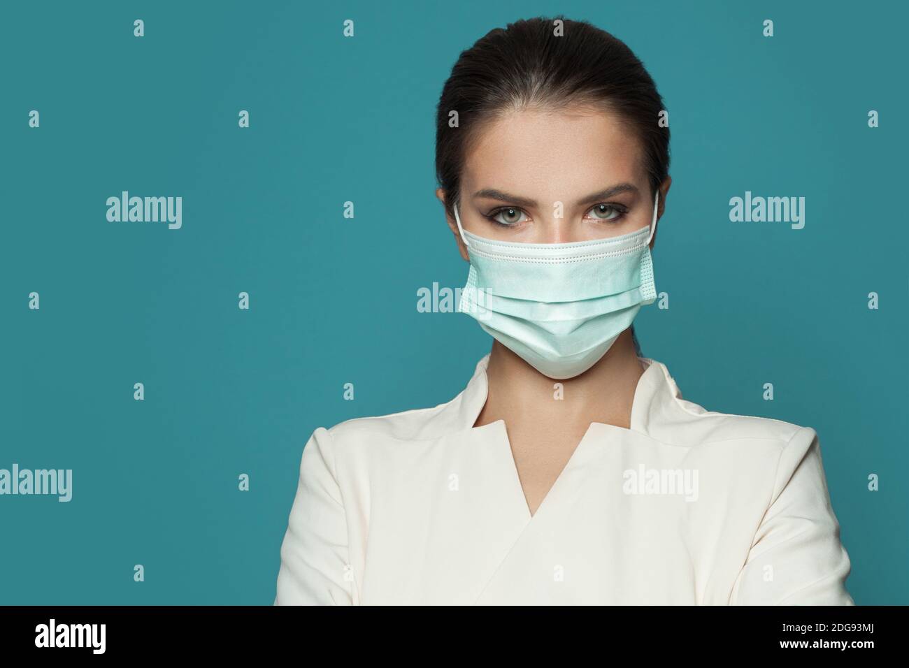 Ritratto di medico donna che indossa una maschera medica protettiva viso e. uniforme professionale su sfondo blu Foto Stock
