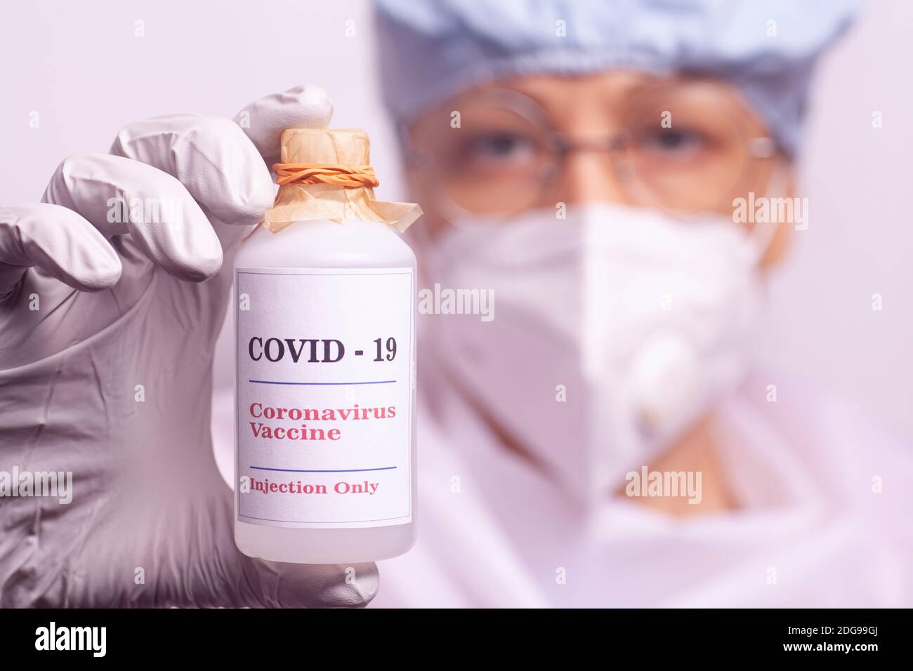 Il medico femminile tiene una bottiglia di vaccino covid-19. Scienziato in abiti sterili sta facendo un vaccino covid-19. Foto Stock