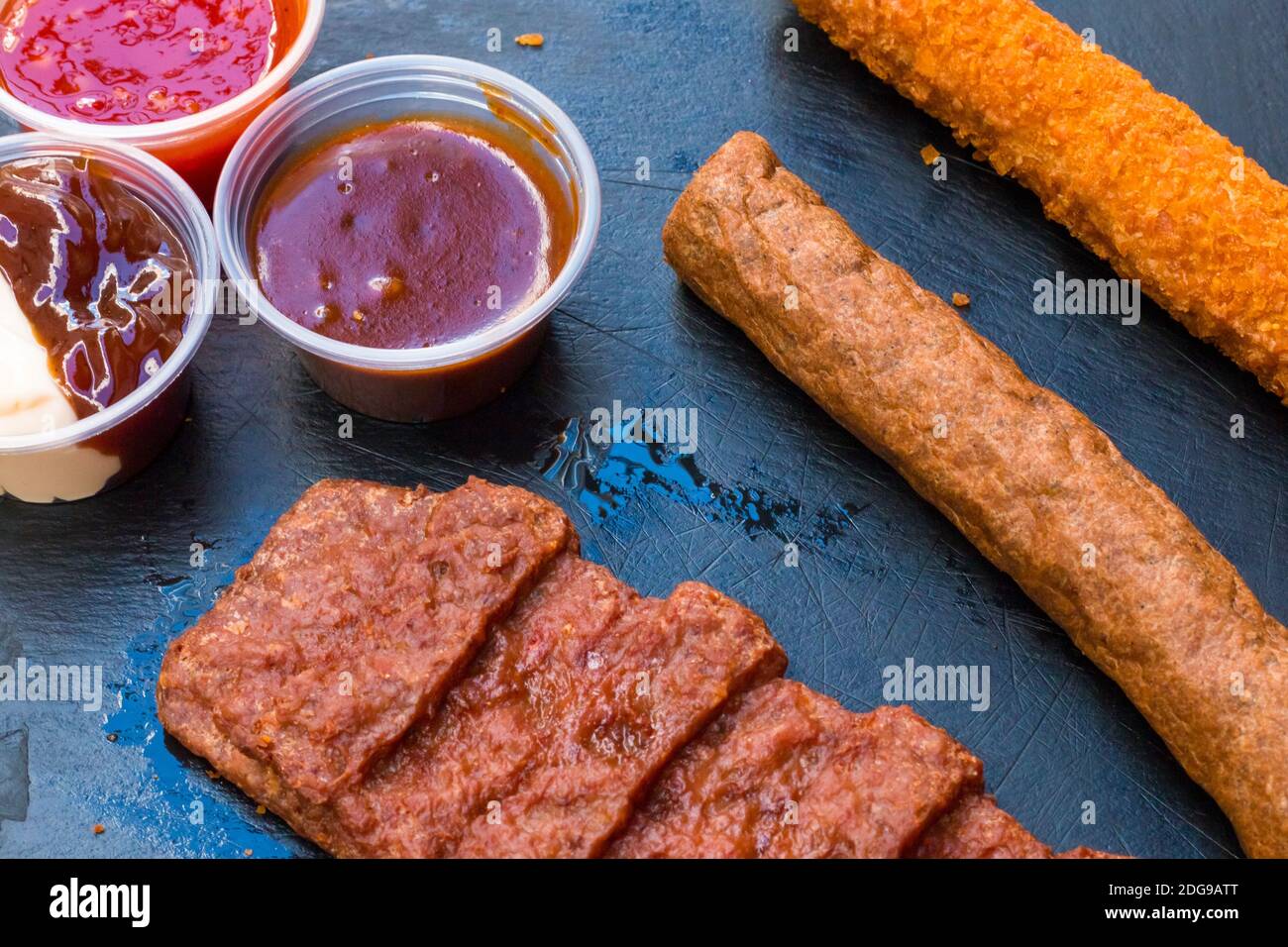 carne fritta diversa. Diversi tipi di bistecca di carne di maiale, filetto di pollo e salsiccia di manzo con alcune salse su sfondo di legno scuro. Grigliate e barbe Foto Stock