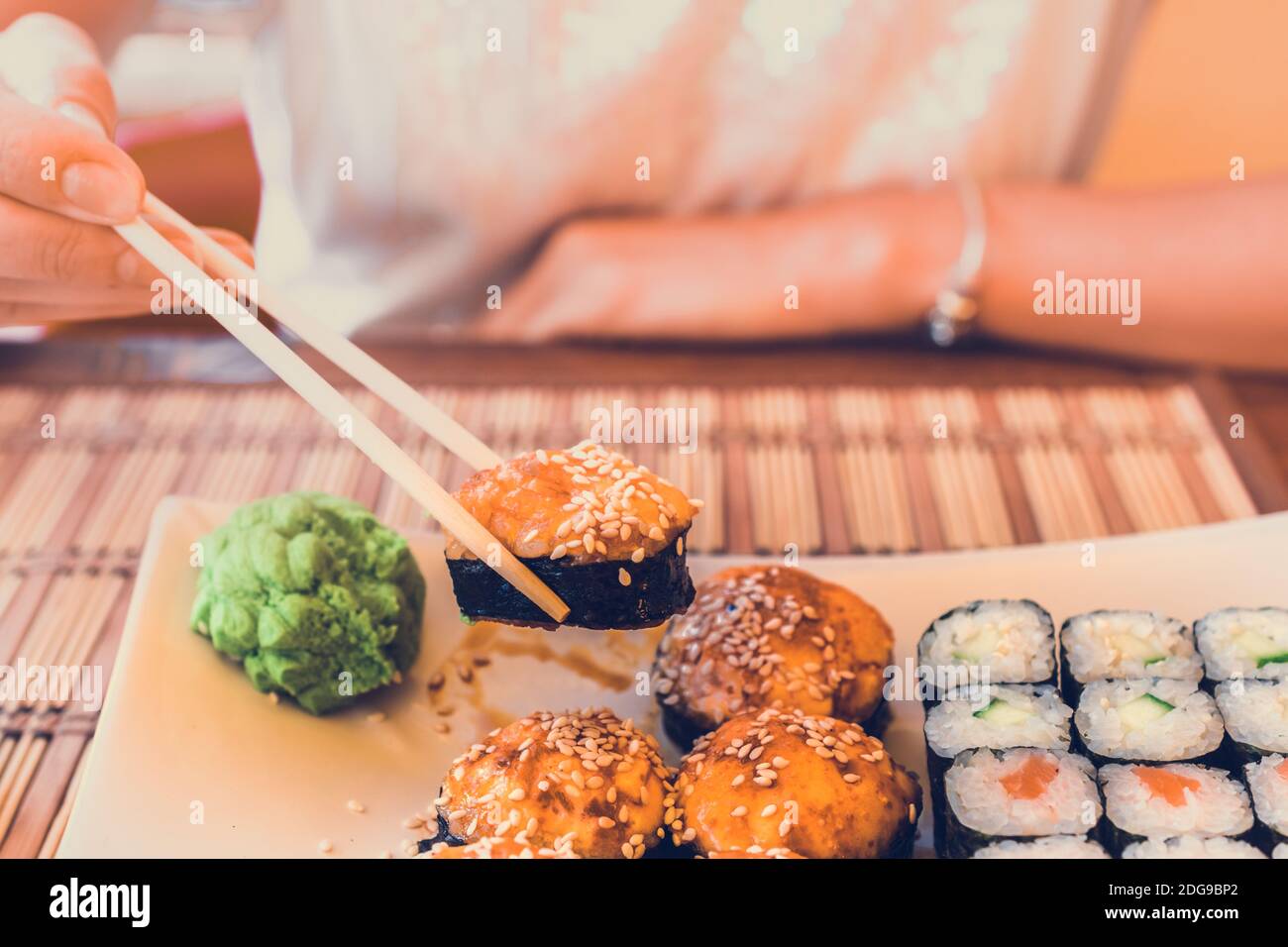 Donna con bacchette asiatiche mangia sushi in street cafe Foto Stock