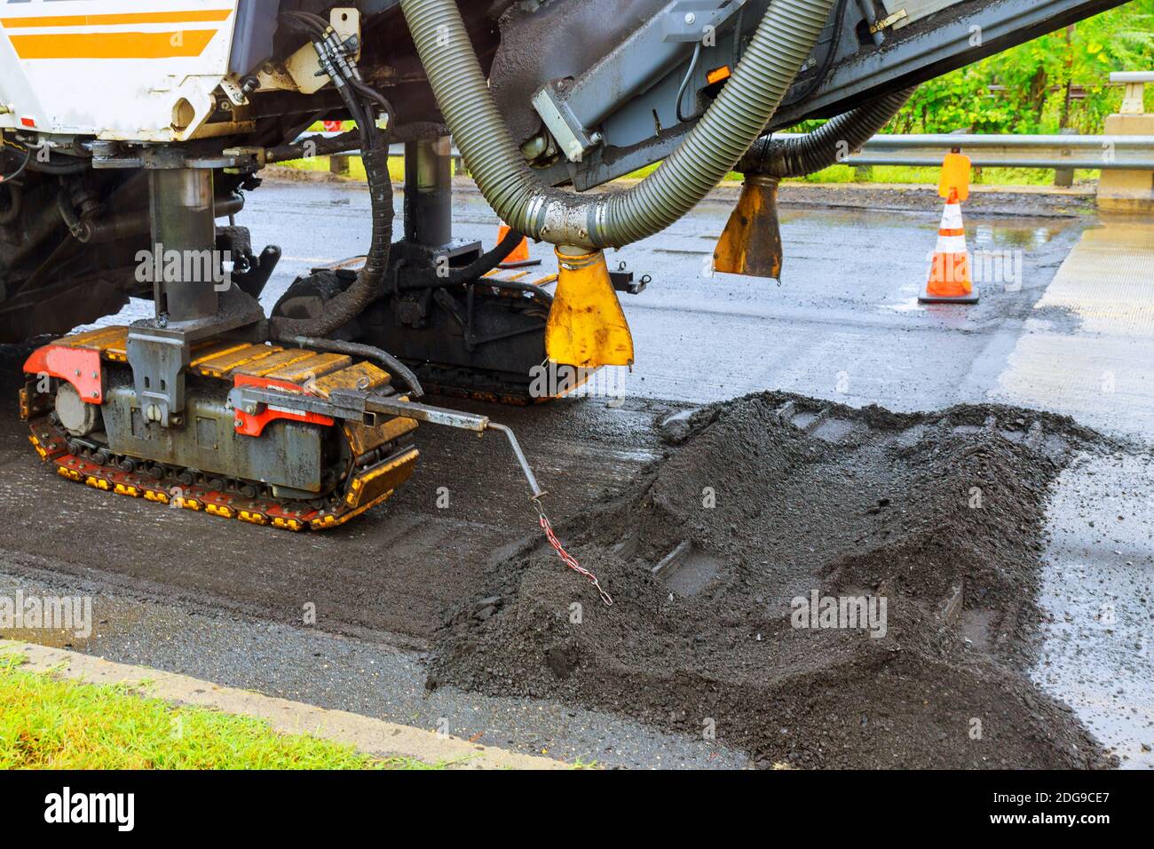 Riparazione di asfalto della città nella strada dell'installazione. Un escavatore arancione scavare una trincea per sostituzione vecchio asfalto Foto Stock