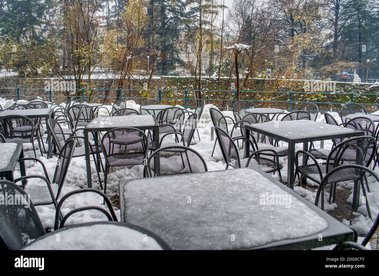 Sedie e tavoli da ristorante incatenati tra loro coperti di neve al Passero di Merano, Italia. Nessun segno di attività perché COVID-19. Foto Stock