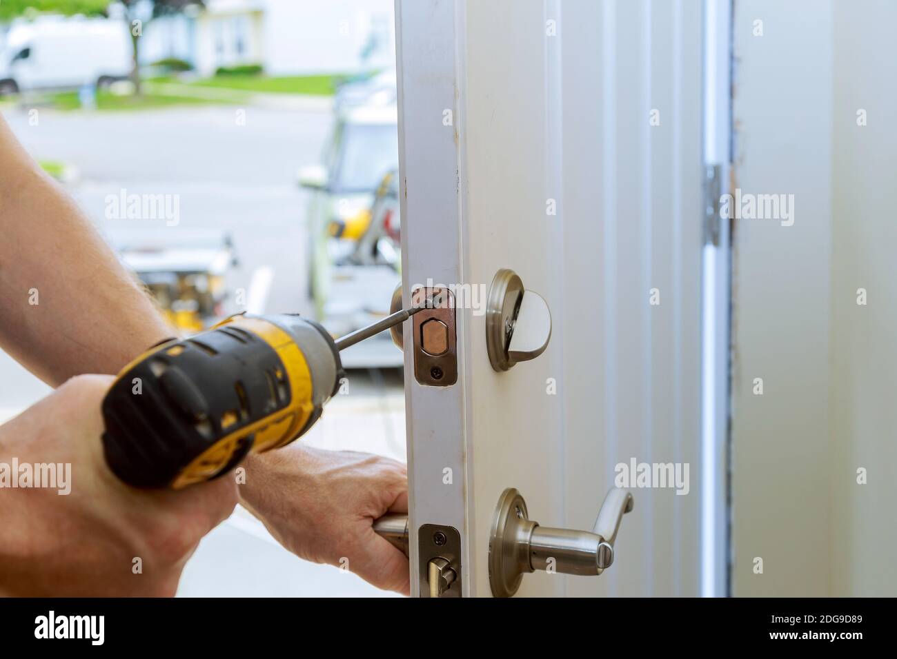 Uomo che ripara il pomello della porta. Chiusura delle mani del lavoratore che installa il nuovo armadietto della porta Foto Stock