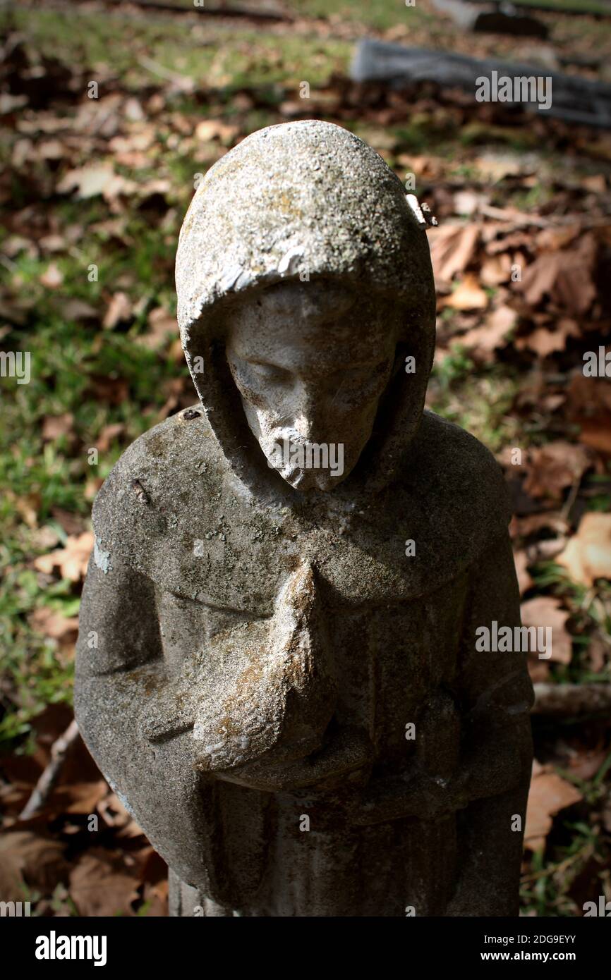 Una vignetta di una piccola figurina cementizia di San Francesco d'Assisi che tiene delicatamente un uccello Foto Stock