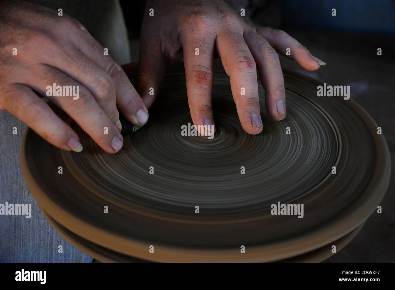 Primo piano delle mani dell'uomo utilizzando una ruota di vasaio per creare pentole e piatti tradizionali in ceramica a Trinidad, Cuba Foto Stock