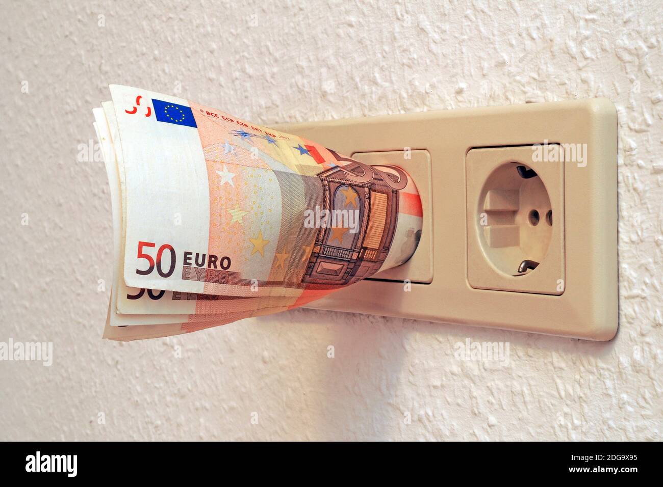 Symbolfoto Energiekosten, Euroscheine in der Steckdose Foto Stock