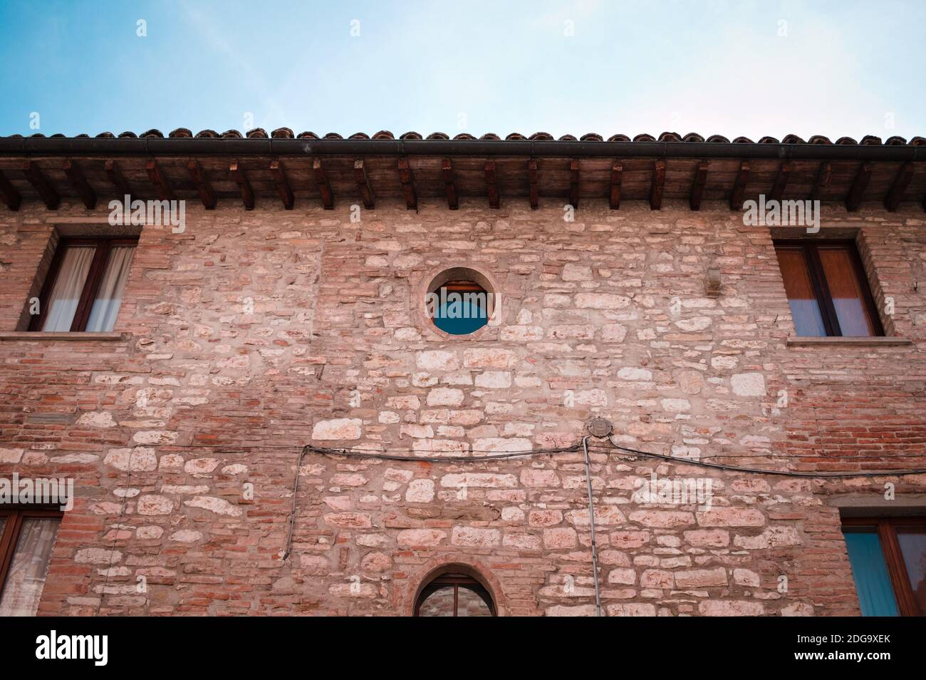 Una vecchia casa in mattoni con finestre rettangolari e circolari in un villaggio italiano (Gubbio, Umbria, Italia) Foto Stock