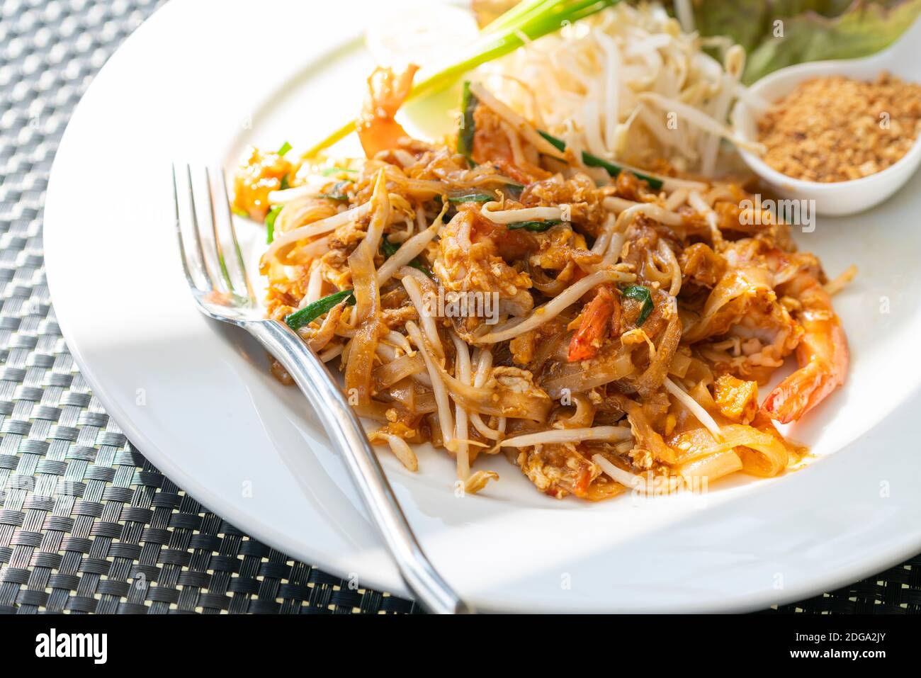 Pad Thai o Thai tradizionale spaghetti fritti con gamberi su piatto bianco, primo piano succosa Pad Thai su piatto bianco con forchetta, bella decorazione alimentare Foto Stock
