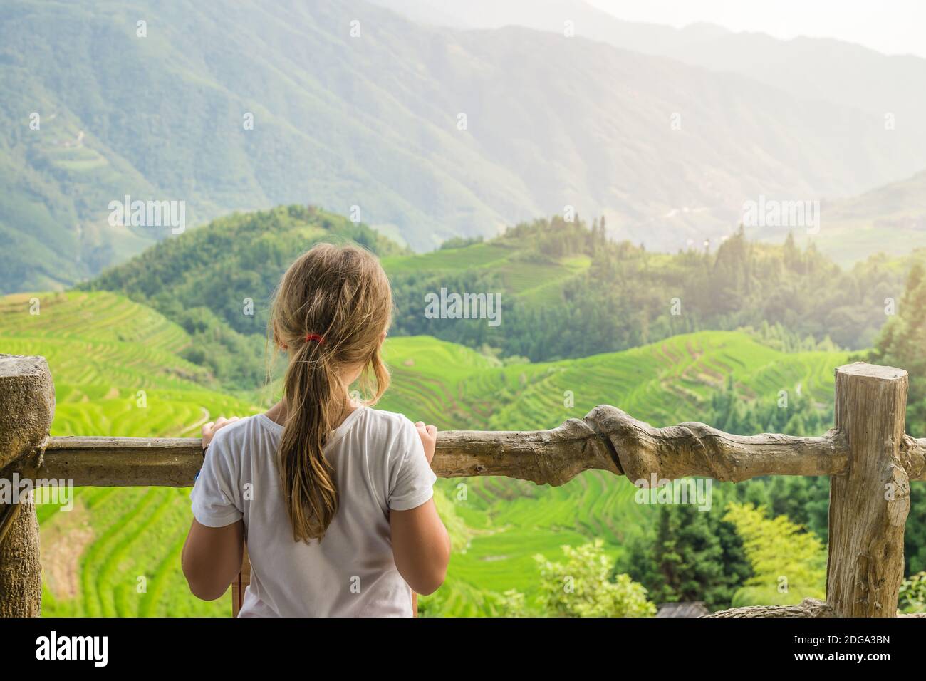 Carina giovane ragazza in piedi su un punto di osservazione nove draghi e cinque tigri e ammirando le cascate a strati Longji Rice terrazze, Pingan villaggio, GUI settentrionale Foto Stock