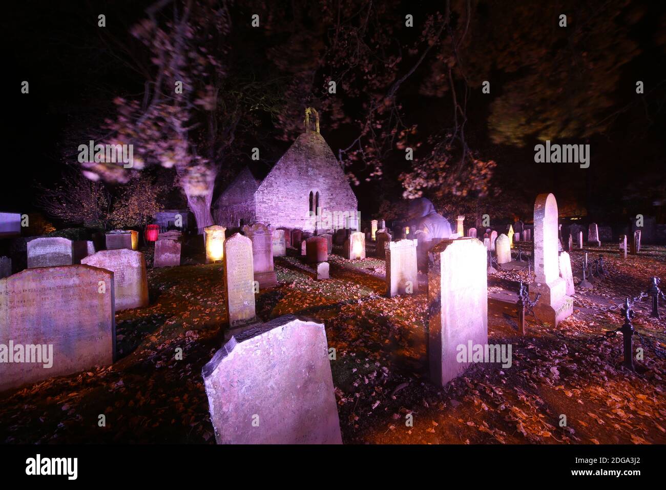 Auld Kirk, Alloway , Sud Ayrshire, Scozia, Regno Unito. Cimitero illuminato per Halloween. Figura annodata offuscata in amonst le tombe parte invisibile Foto Stock
