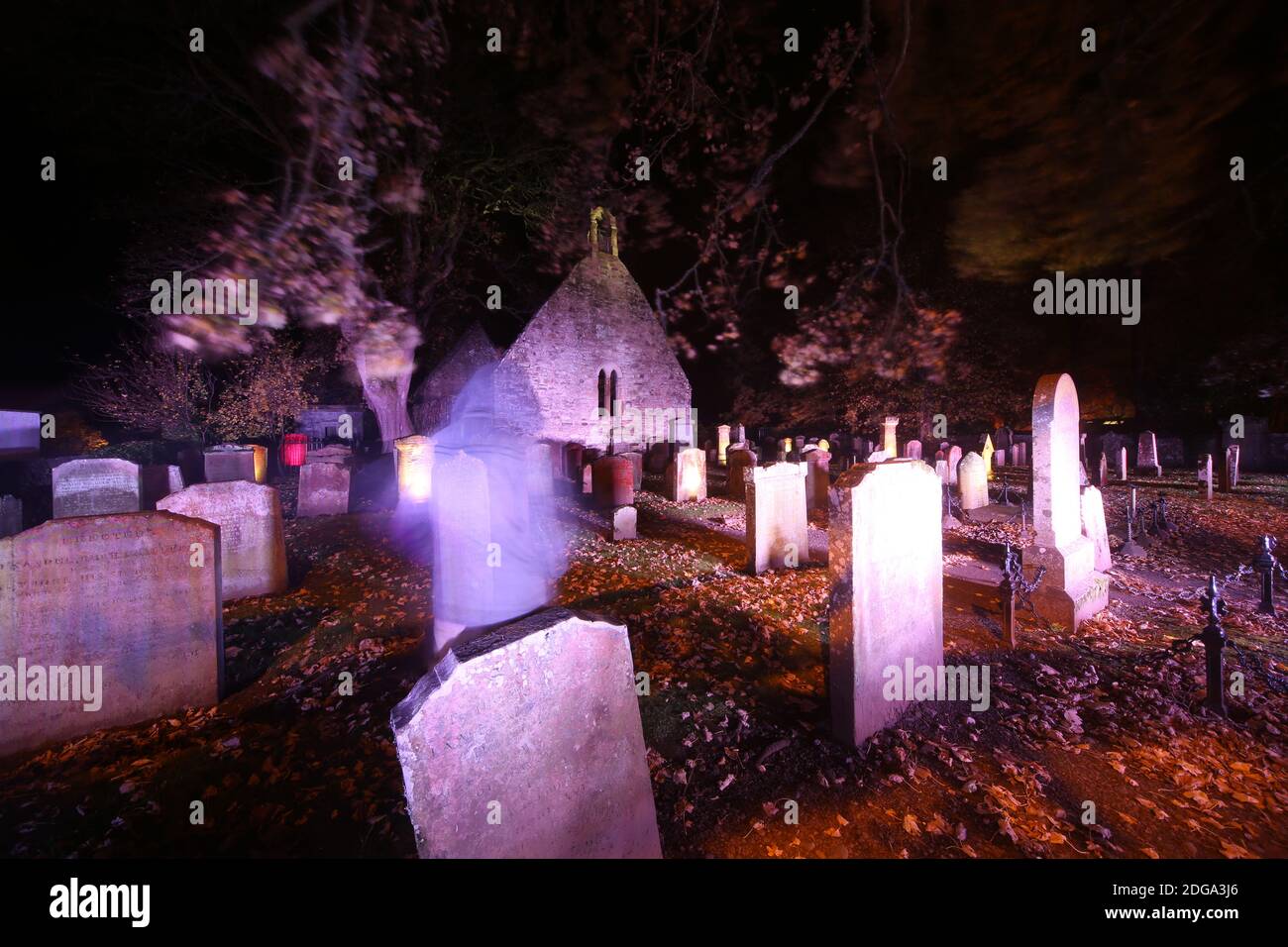 Auld Kirk, Alloway , Sud Ayrshire, Scozia, Regno Unito. Cimitero illuminato per Halloween. Figura annodata offuscata in amonst le tombe parte invisibile Foto Stock