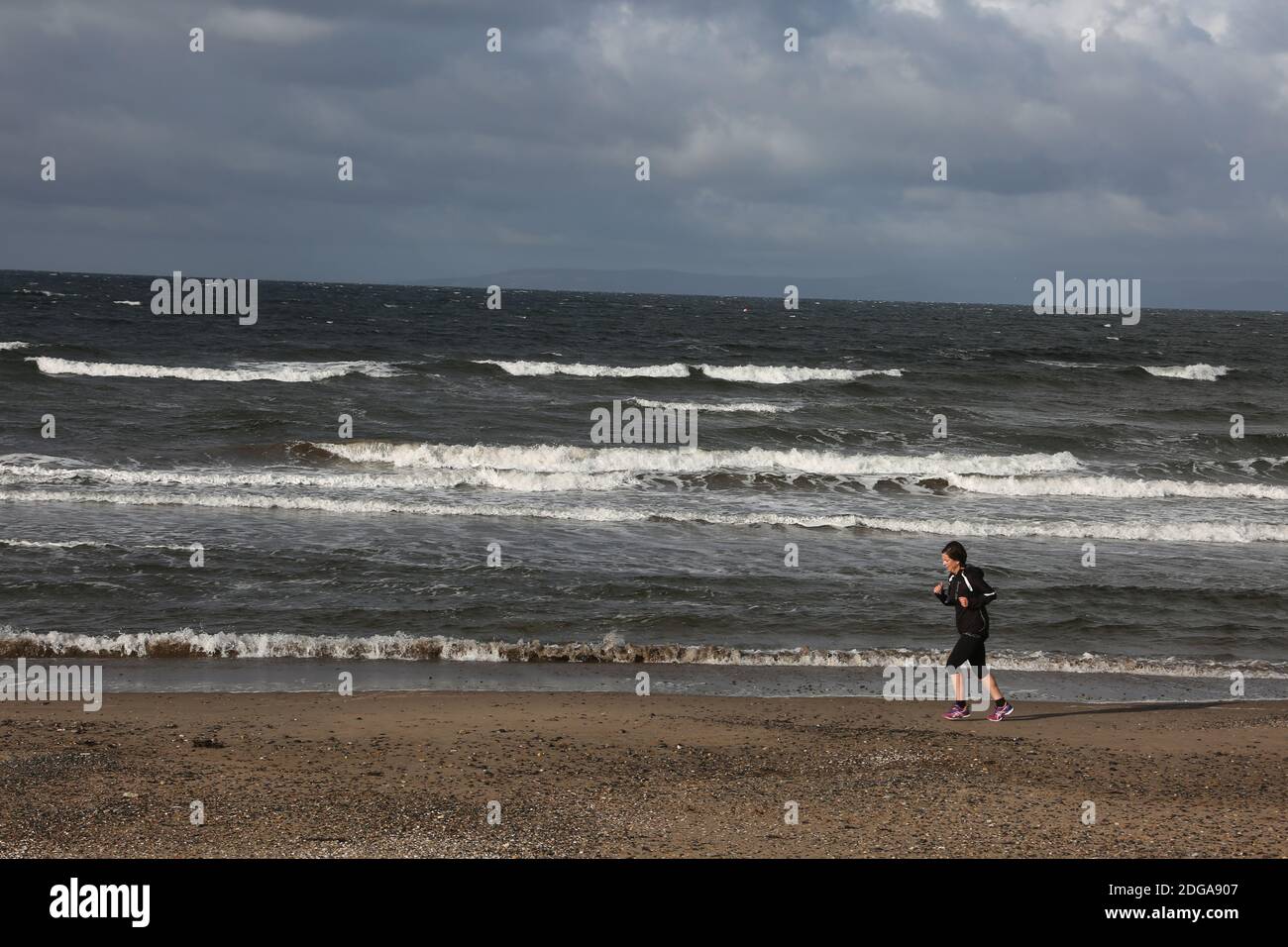 Ayr Beach, Ayrshire, Scozia, Regno Unito, Lone Jogger in spiaggia con il tempo invernale Foto Stock