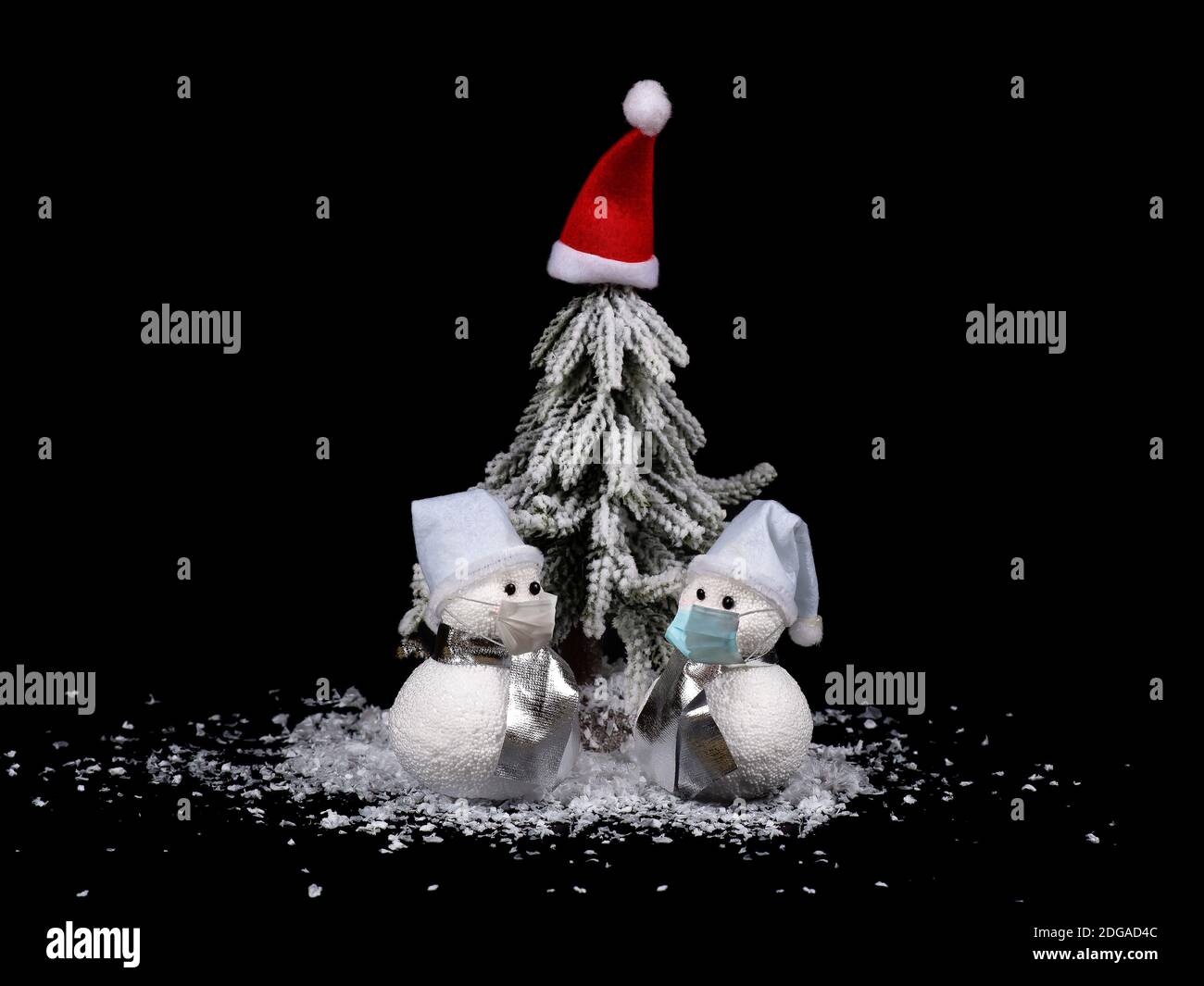 Anno nuovo e composizione di Natale. Pupazzi di neve davanti all'albero di Natale con maschere. Coronavirus Concept background. Foto Stock