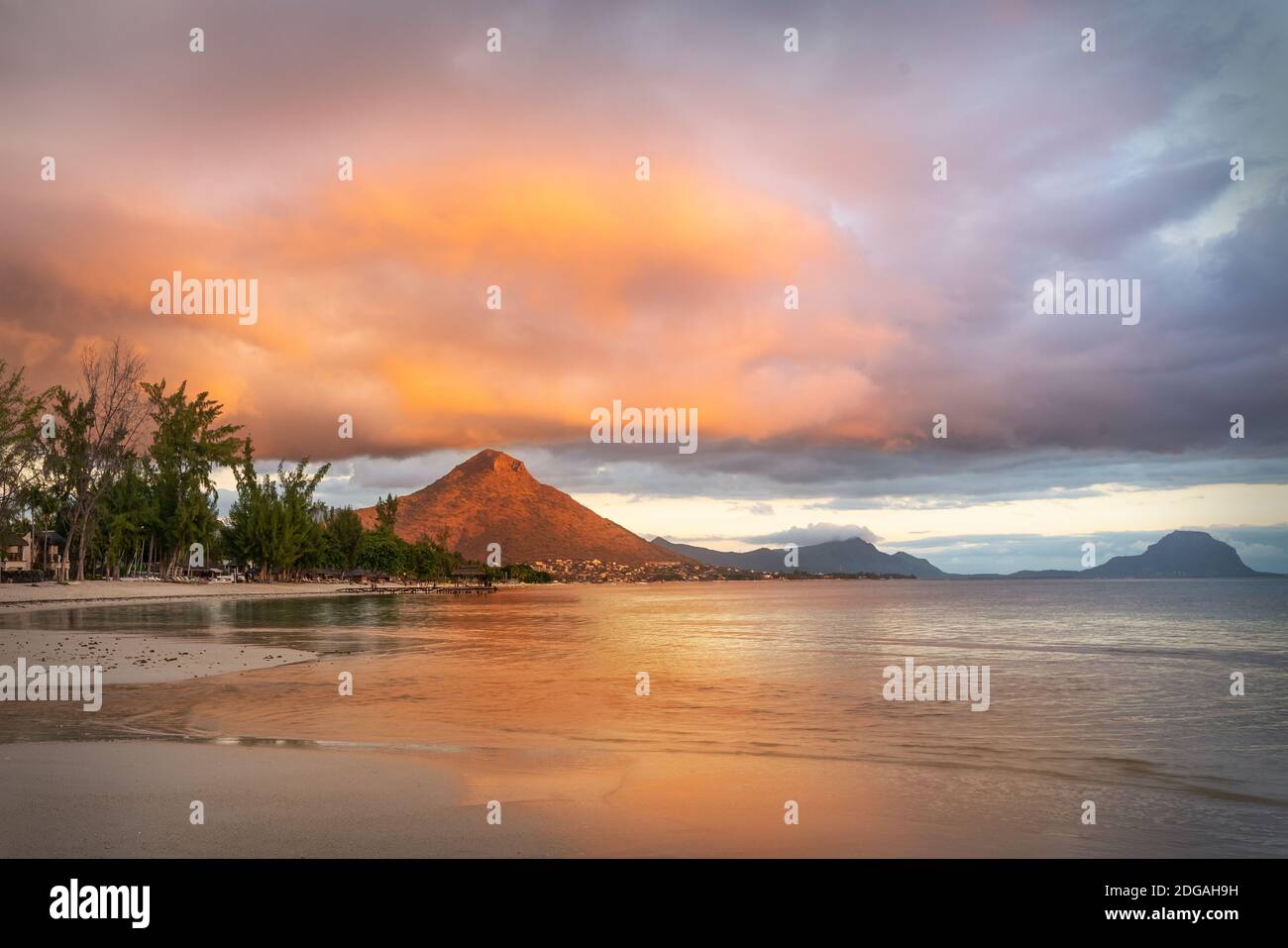 Spiaggia di Flic en Flac con hotel di lusso e palme al tramonto, dietro la montagna Tourelle du Tamarin, Mauritius, Africa Foto Stock