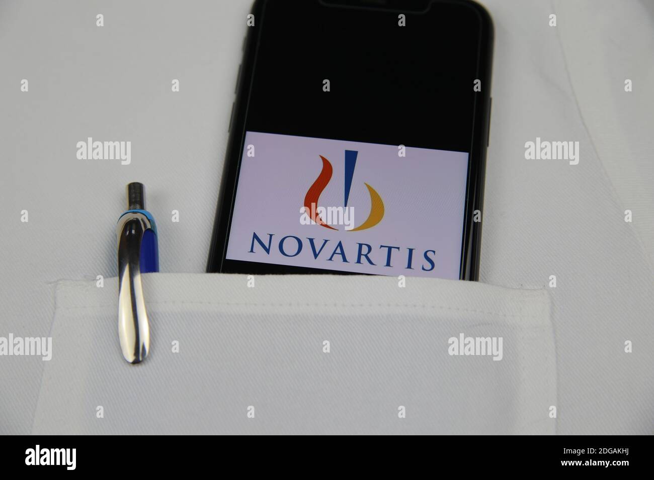 Viersen, Germania - 9 aprile. 2020: Primo piano dello schermo del telefono cellulare con la scritta del logo della società farmaceutica Novartis in tasca di medici bianchi co Foto Stock