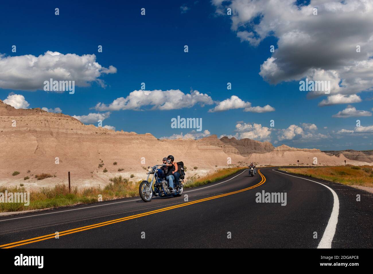Badlands National Park, South Dakota - 9 agosto 2014: Motociclisti che cavalcano le loro moto chopper su una strada sterrata al Badlands National Park. Foto Stock