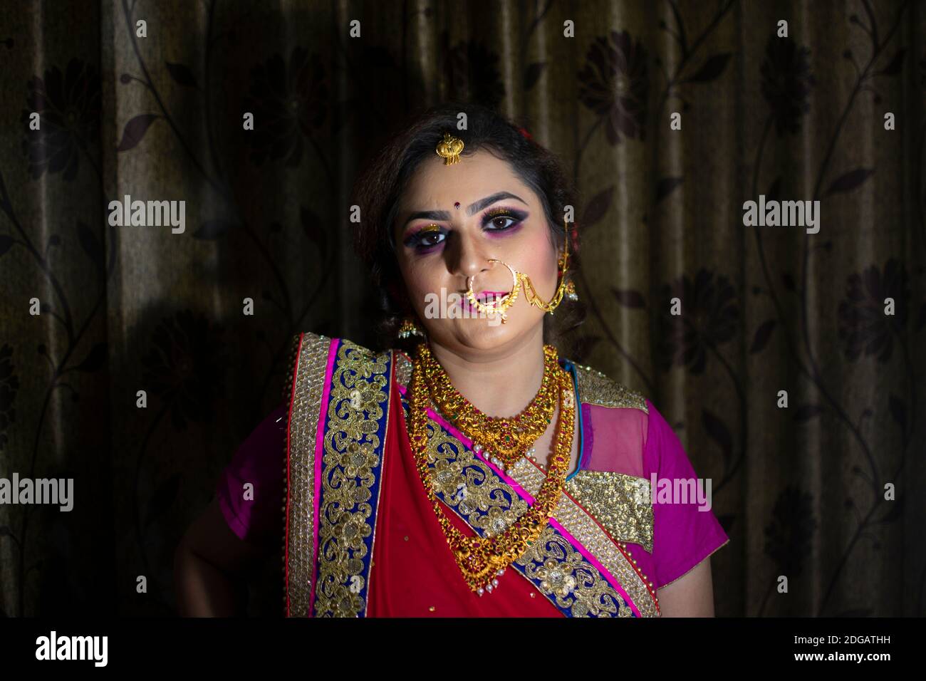 Una bella ragazza indiana in abito da sposa con saree rosse e ornamenti d'oro Foto Stock