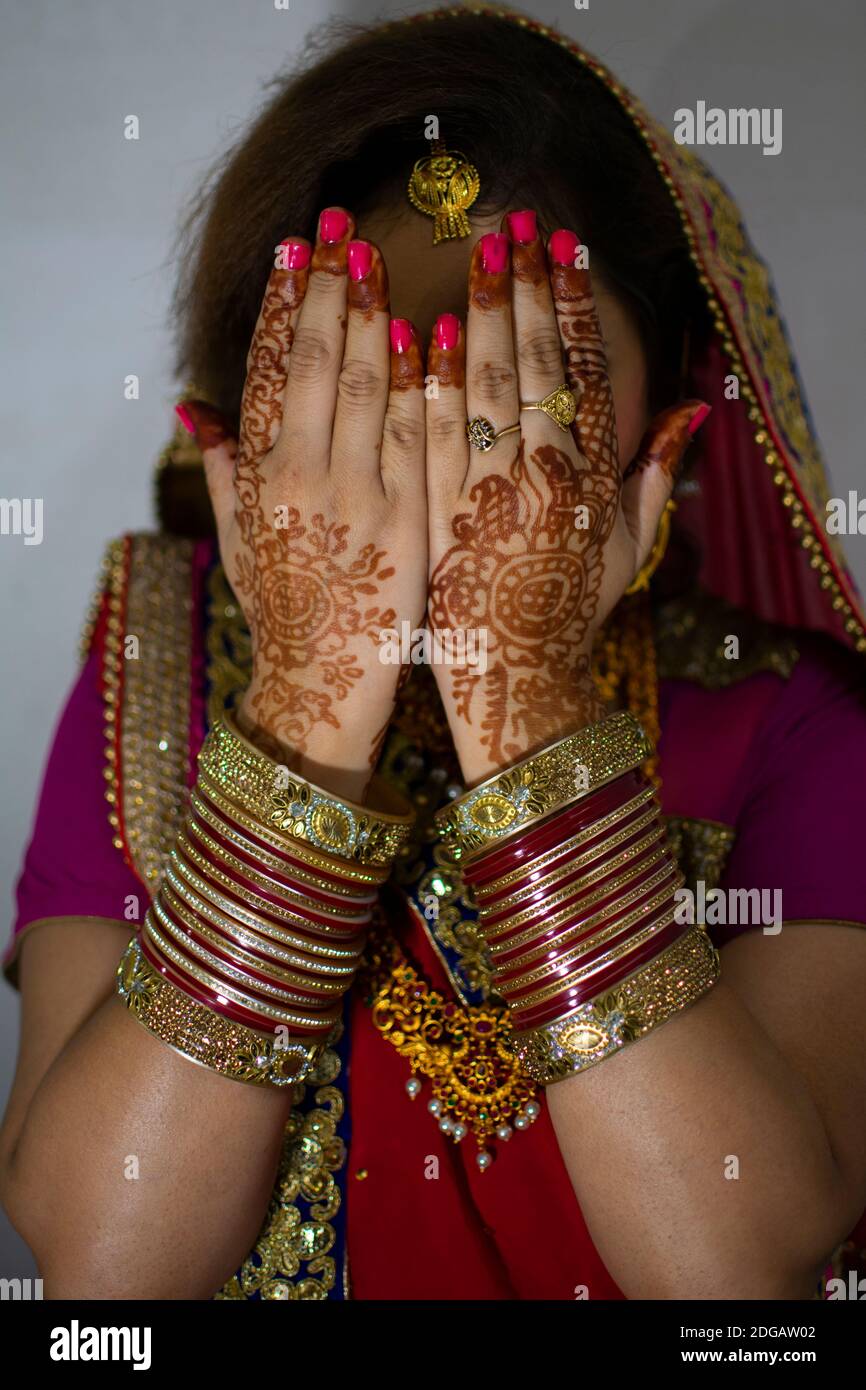 una bella ragazza indiana in abito da sposa con saree rosse e ornamenti d'oro che mostrano il tatuaggio chiamato mehindi Foto Stock