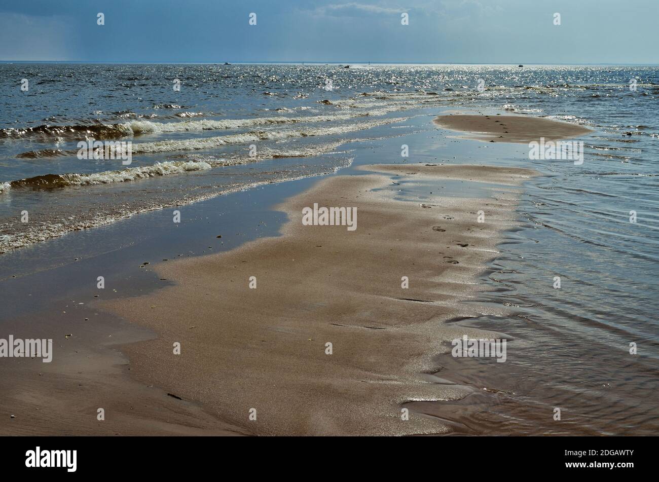 Spiaggia di sabbia vicino al mare. Le onde calde si lavano sopra la riva. Foto Stock