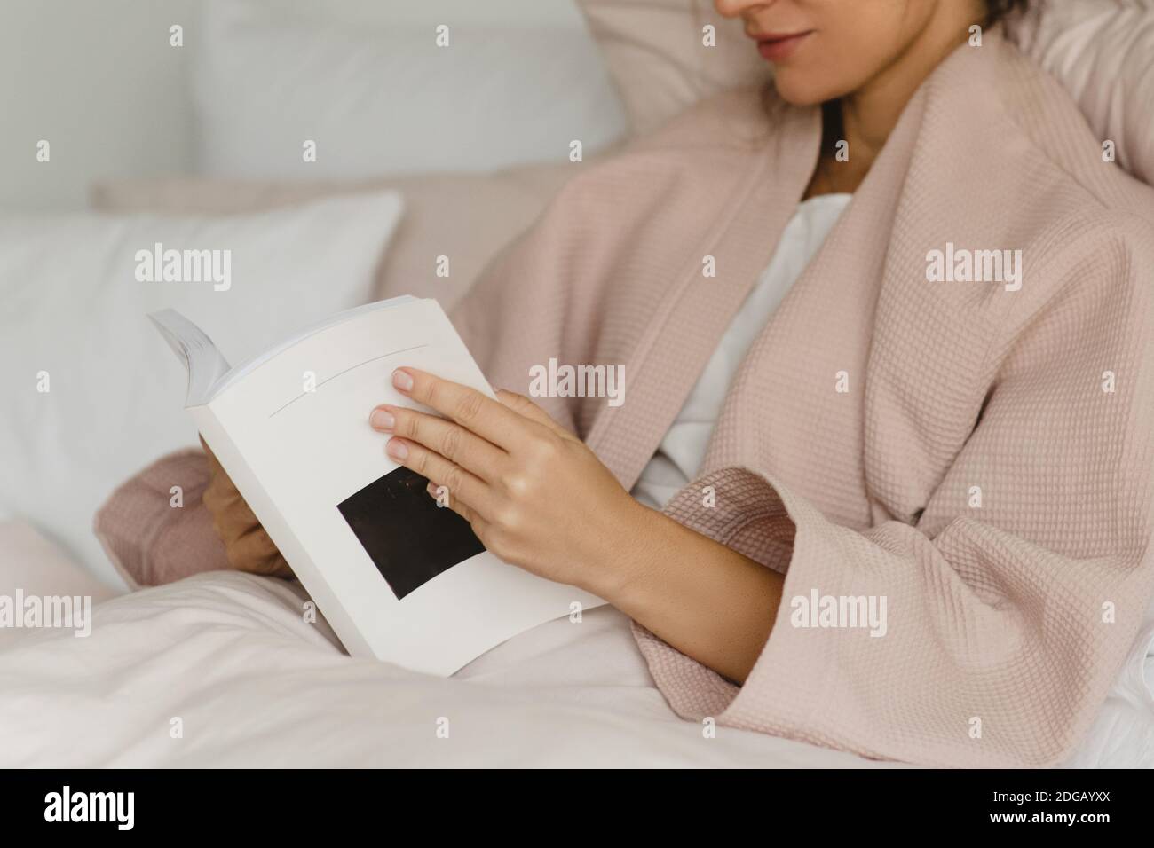 Primo piano di bella donna che si trova a letto e leggere un libro. Foto Stock