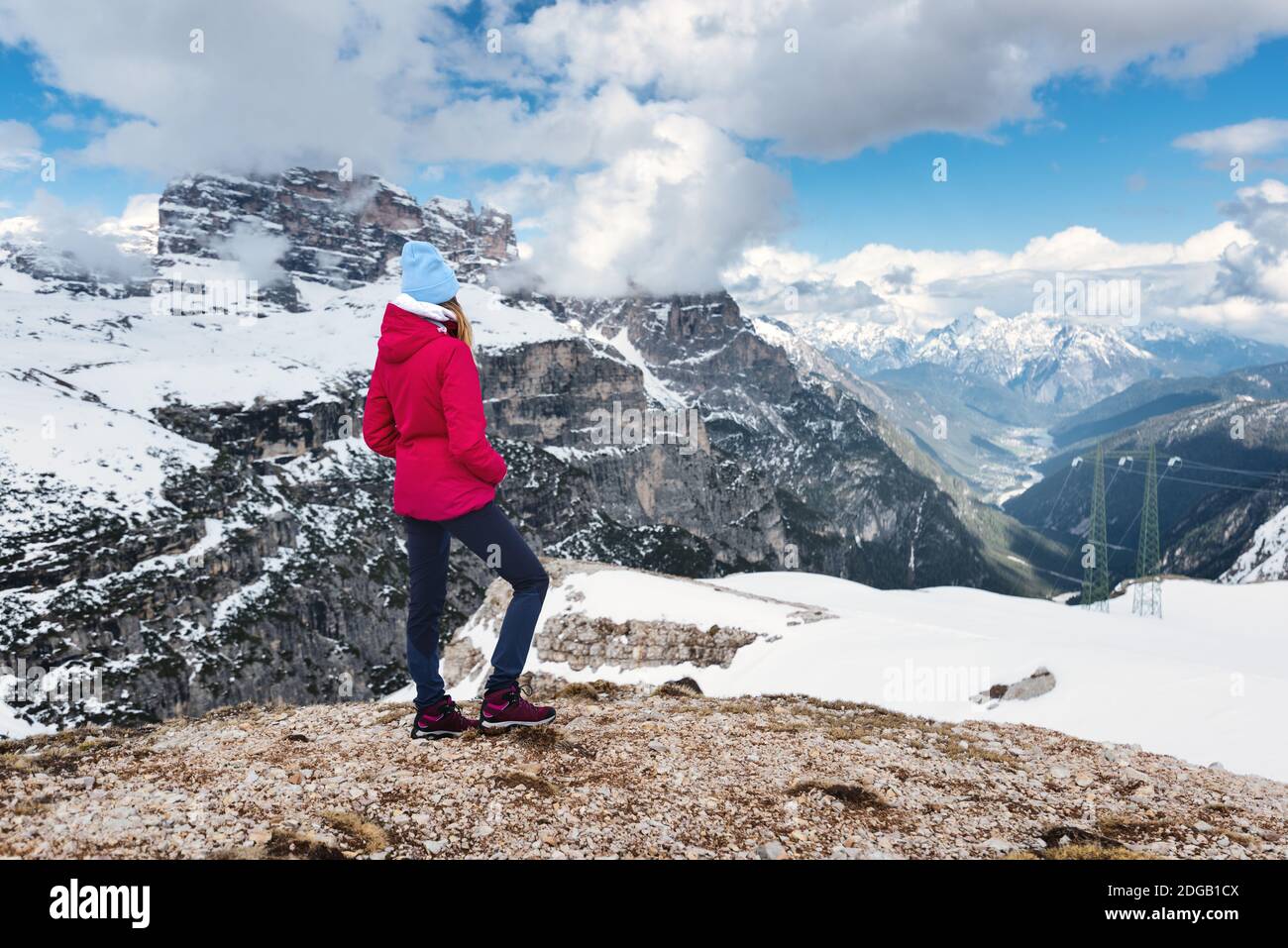 Giovane donna in giacca rossa sulla collina contro neve montagne Foto Stock