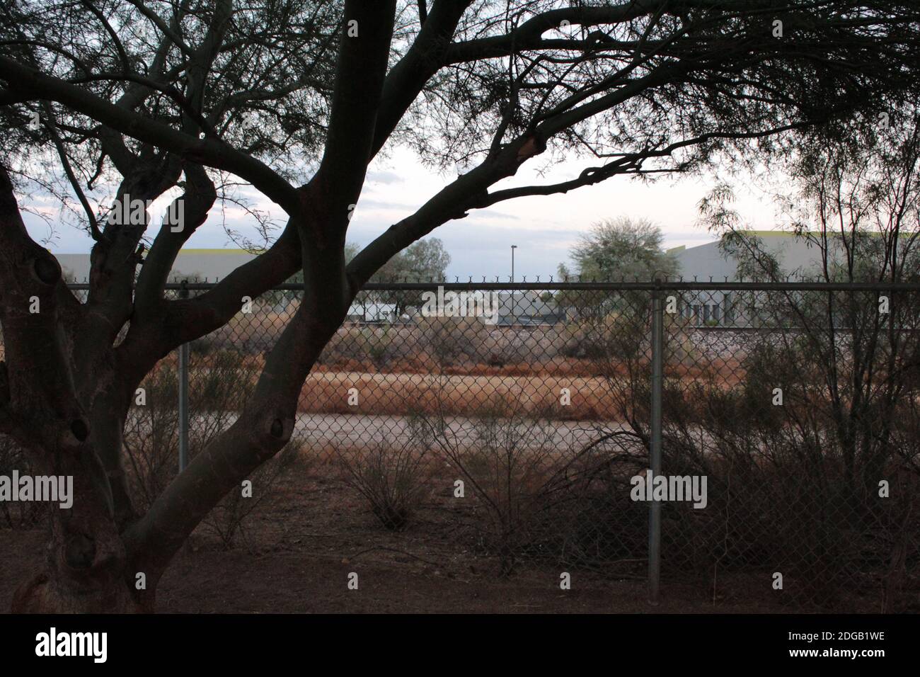 Immagine di binari ferroviari ad accesso limitato con parco industriale-commerciale visibile sullo sfondo. Foto Stock