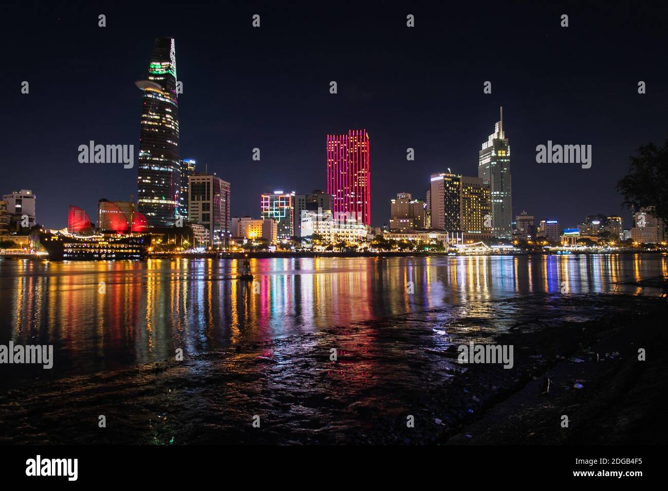 Vista notturna panoramica e colorata dello skyline della città di ho Chi Minh riflessa sul fiume Saigon. I grattacieli e gli edifici moderni si trovano nel quartiere 1. Foto Stock