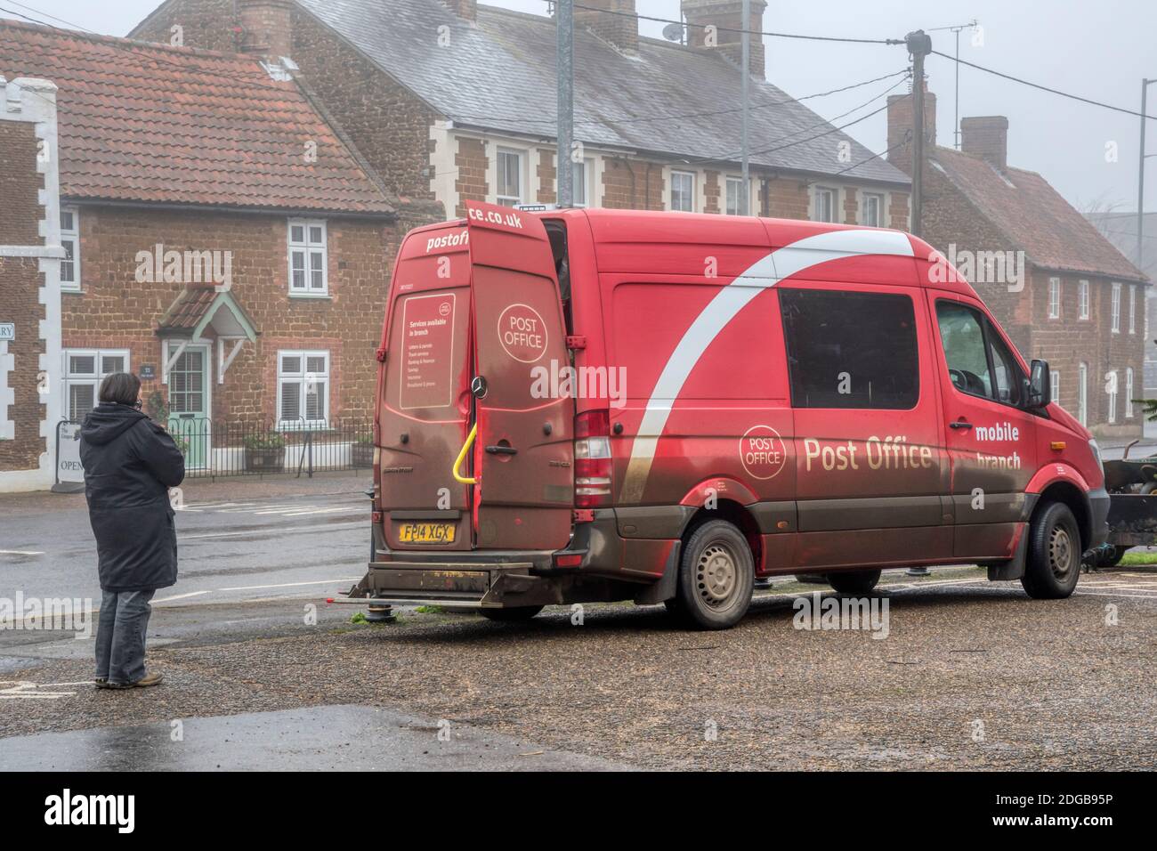 Donna in coda per l'ufficio postale mobile in un giorno invernale foggy a Snettisham, Norfolk. Foto Stock