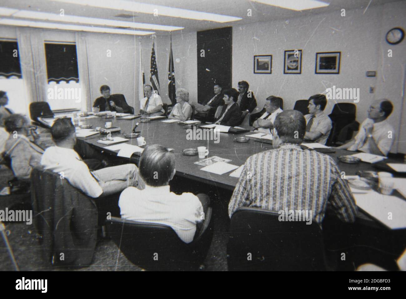 Bella fotografia in bianco e nero degli anni '70 di una riunione d'affari piena di professionisti del colletto bianco in una grande sala conferenze. Foto Stock