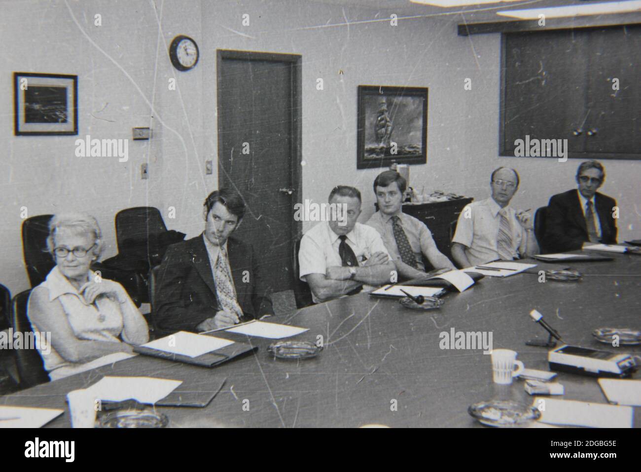 Bella fotografia in bianco e nero degli anni '70 di una riunione d'affari piena di professionisti del colletto bianco in una grande sala conferenze. Foto Stock