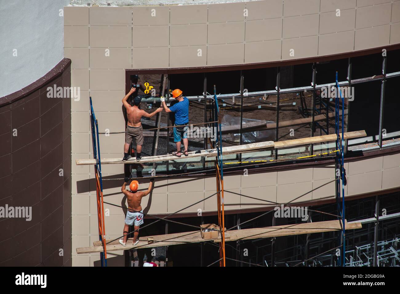 Lavoratori di finestre su un ponteggio in cantiere su un facciata dell'edificio Foto Stock