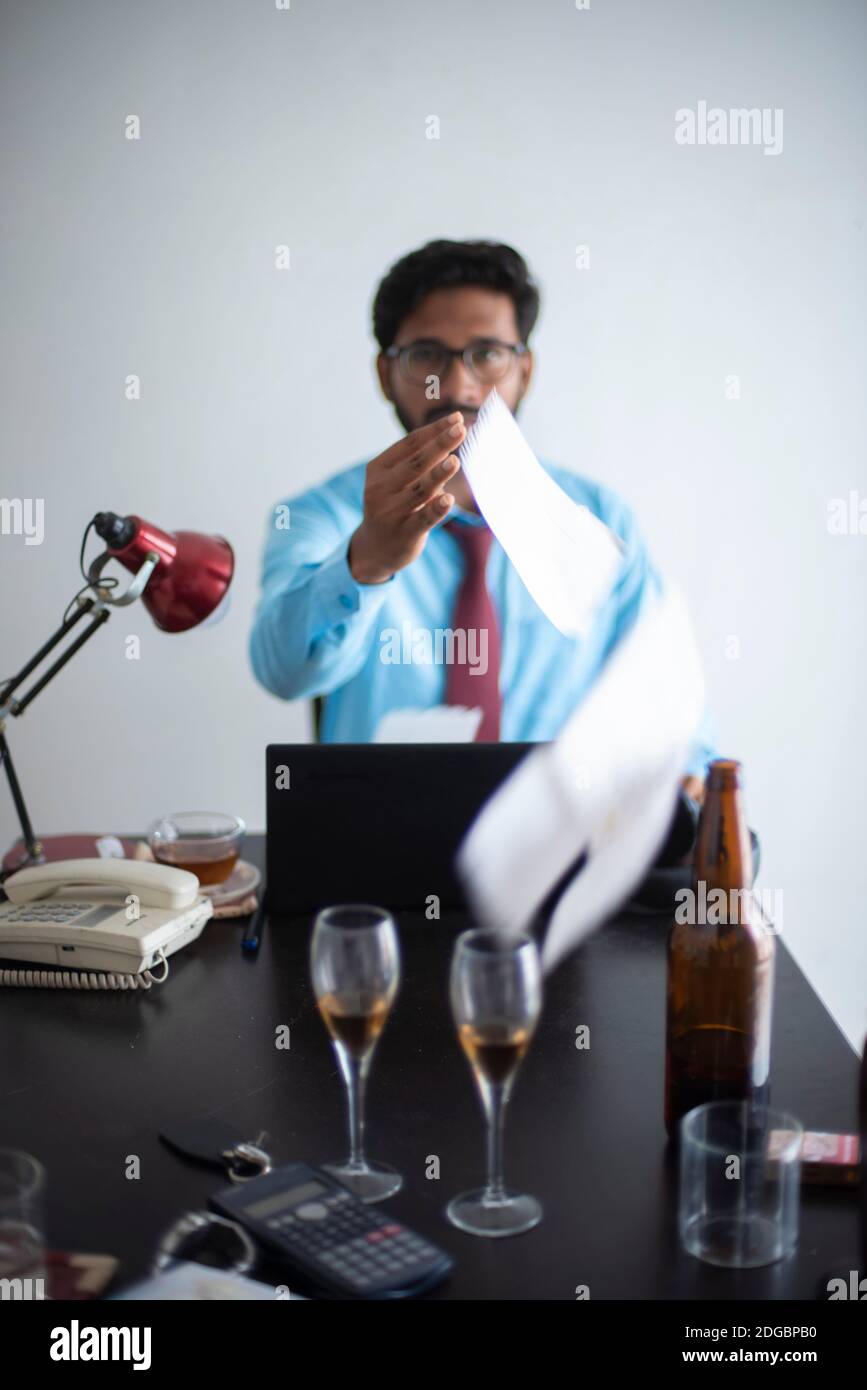 Indiano Bengalese alto, scuro, bella bruna giovane uomo in ufficio indossare godendo di successo mentre si siede su un tavolo da ufficio in un ufficio aziendale / bpo Foto Stock
