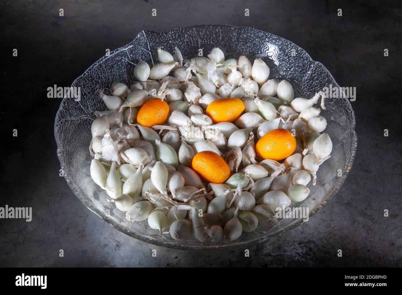 Quattro Kumquat e piccoli cipolle in lastra di vetro. Shot su piastra di metallo vecchia. Miscela di ingredienti sani. Spot Studio Shot. Foto Stock