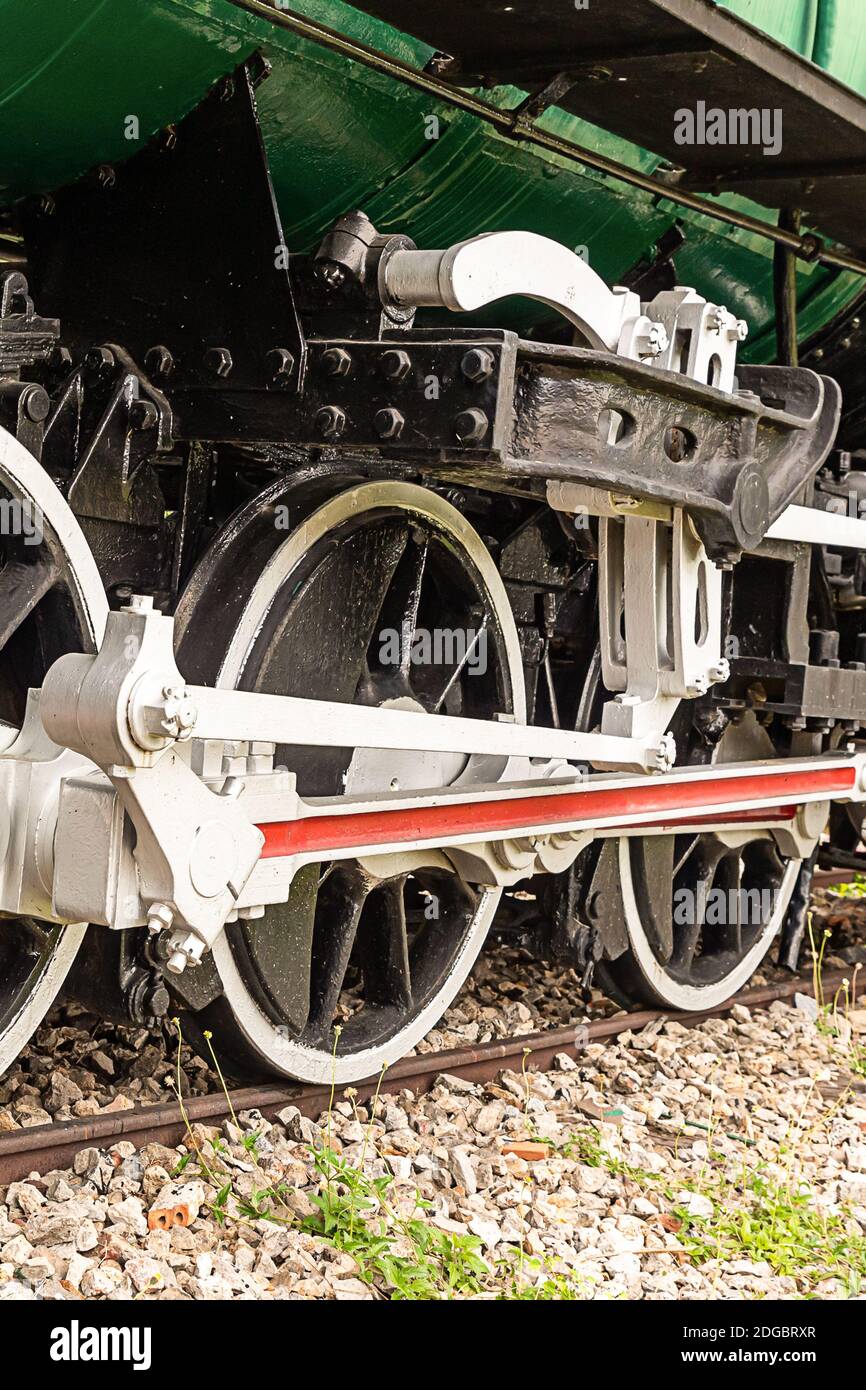 Vecchia locomotiva grandi ruote di ferro con un bordo bianco si trova in primo piano sui sentieri Foto Stock