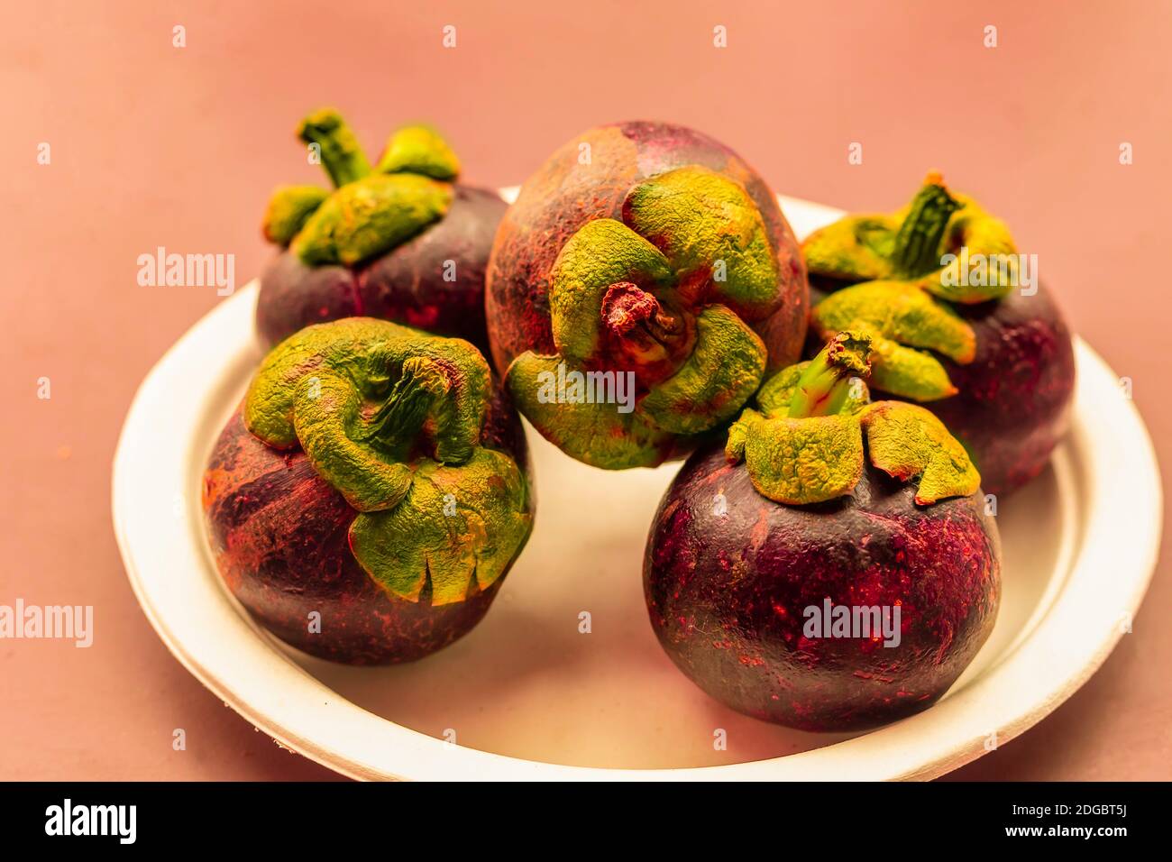 Mangosteen frutti interi giacciono su un piatto bianco da vicino dessert asia Foto Stock