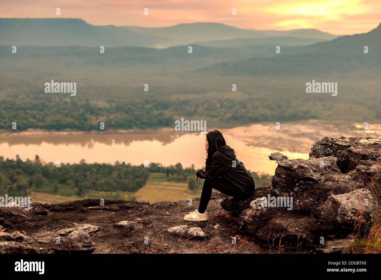 Donna seduta su una roccia che guarda alla vista, Ubon Ratchathani, Isan, Thailandia Foto Stock