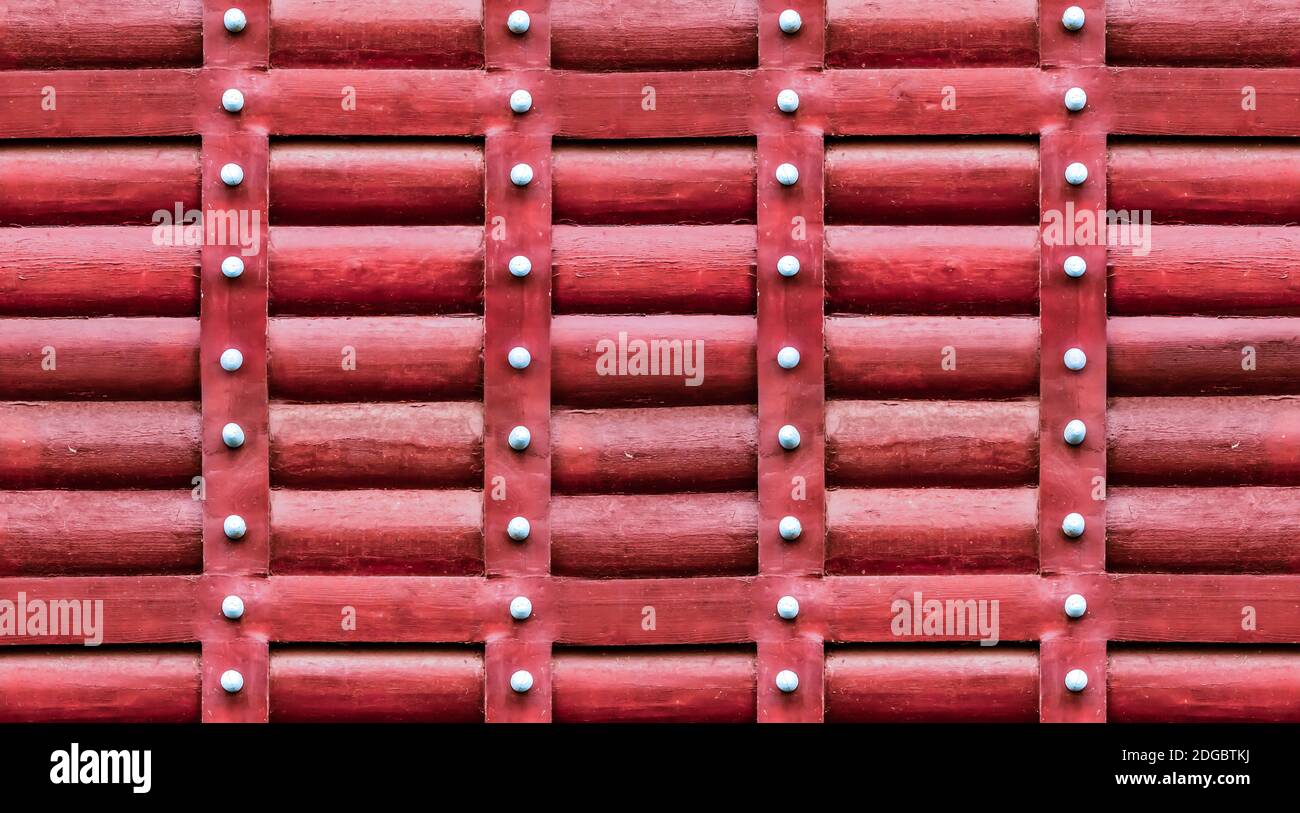 Modello di legno rosso, la parete è fatta di tronchi con strisce di ferro verticali e rivetti Foto Stock