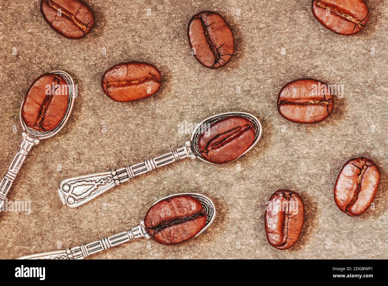 Vista dall'alto dei cucchiai metallici e dei chicchi di caffè tostati aromatizzati sullo sfondo del sacco di burlap, vintage Foto Stock