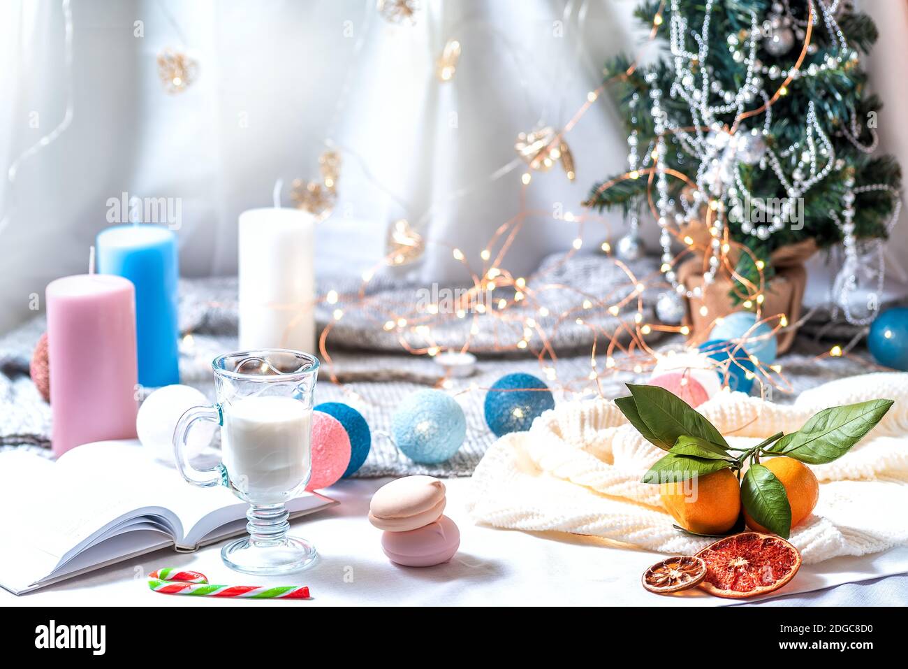 Romantico inverno e decorazione degli interni di stile di Capodanno con una candela, libro, ghirlanda e vetro di m Foto Stock