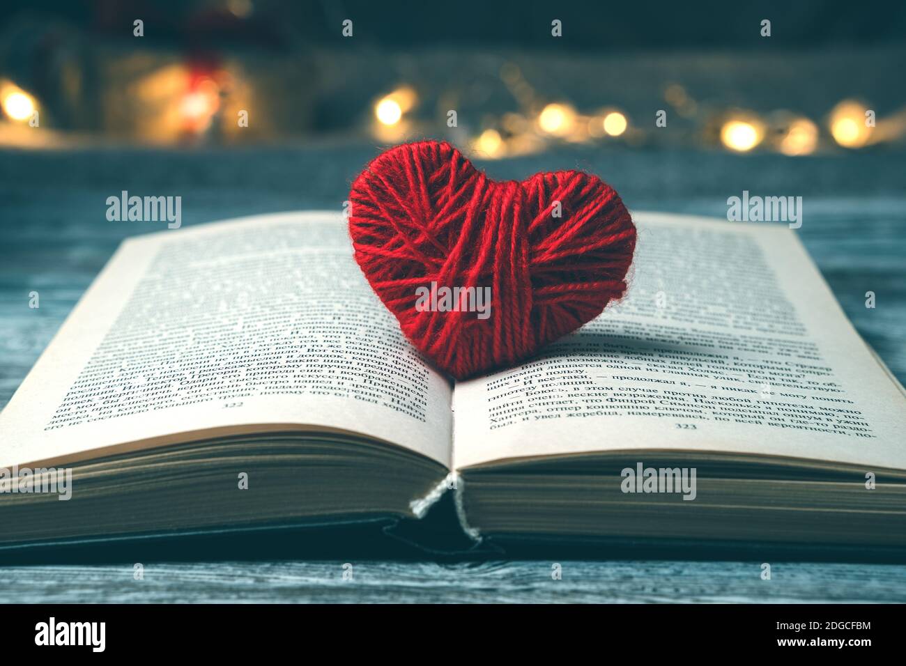 Un libro con un cuore rosso su uno sfondo scuro con luci. Foto Stock