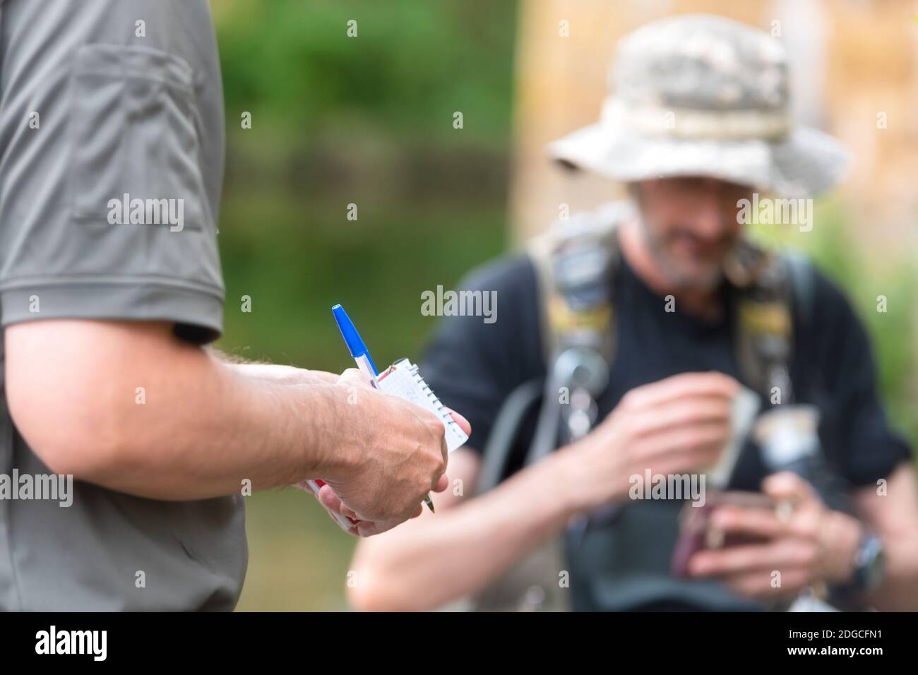 Poliziotto o Ranger che controlla la licenza di pescatore nel fiume. Ispezione della pesca. Legge. Foto Stock