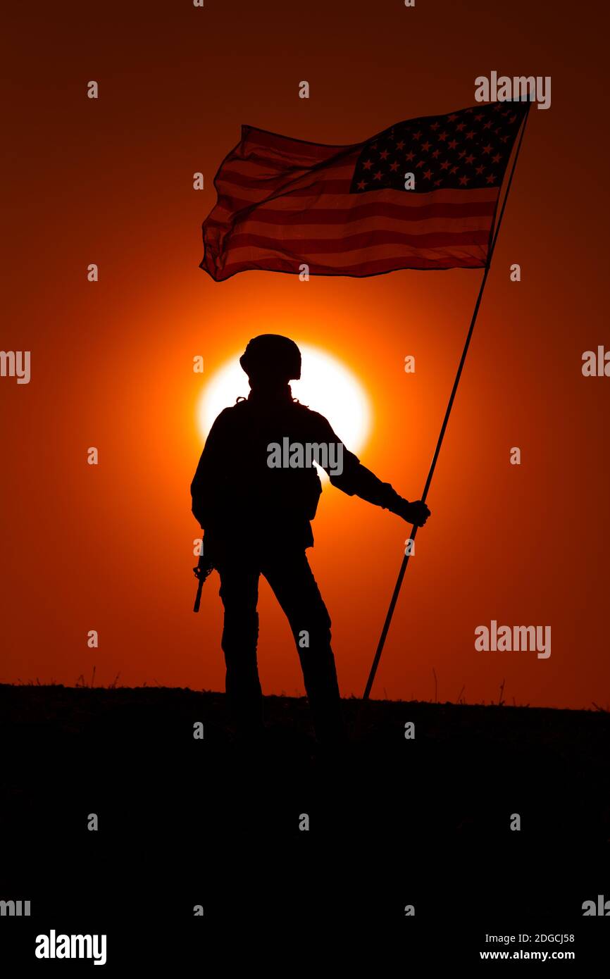 Silhouette del soldato di fanteria dell'esercito degli Stati Uniti, il combattente del corpo dei Marines degli Stati Uniti in piedi all'orizzonte del tramonto con la bandiera nazionale degli Stati Uniti sventolante. Eroismo dei soldati e vittoria in battaglia, onorando gli eroi caduti Foto Stock