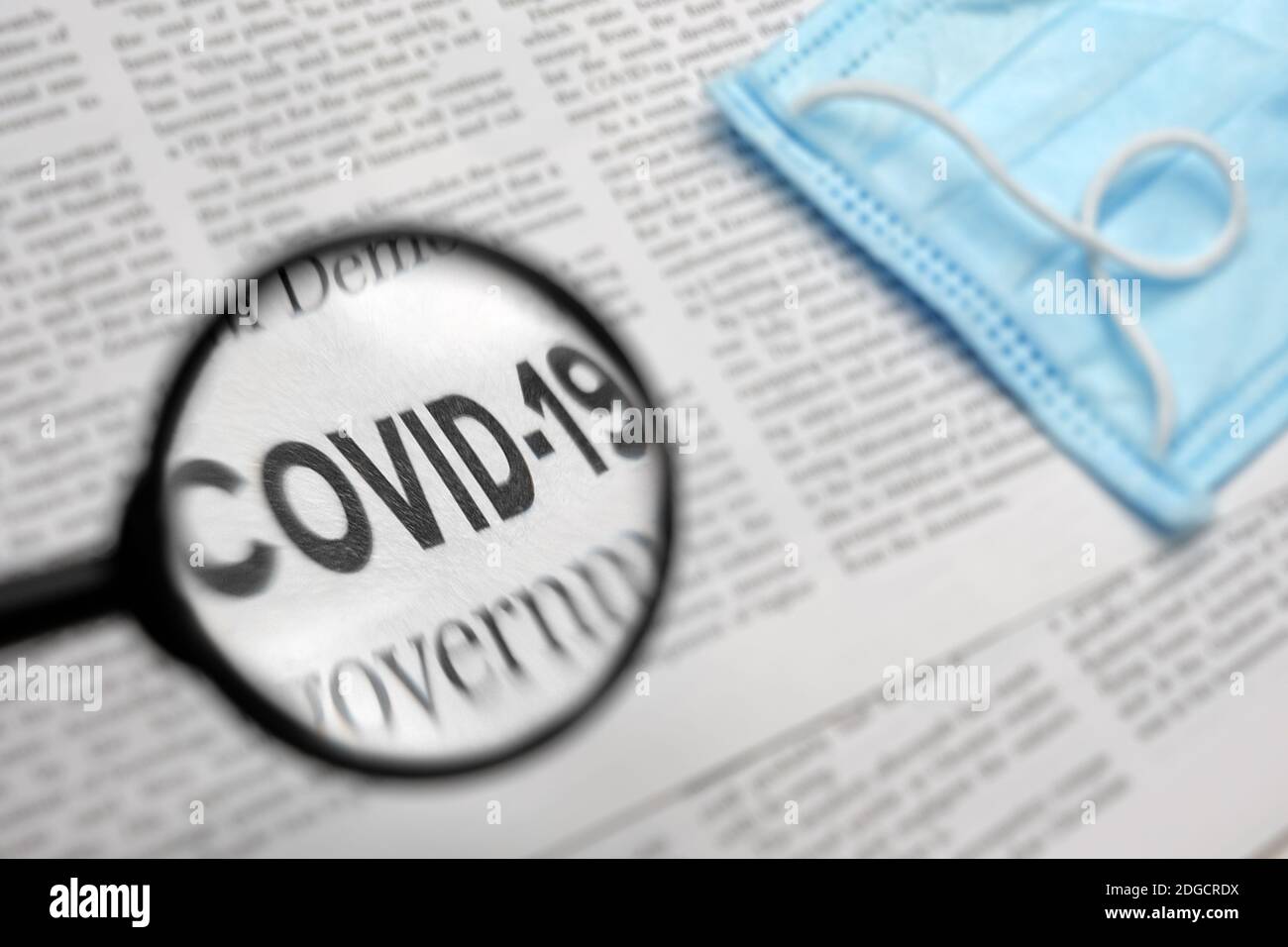 Articolo di giornale con il Covid titolo 19. Lettura dell'articolo sul giornale mediante aumento di una lente d'ingrandimento. Notizie relative al virus corona Foto Stock