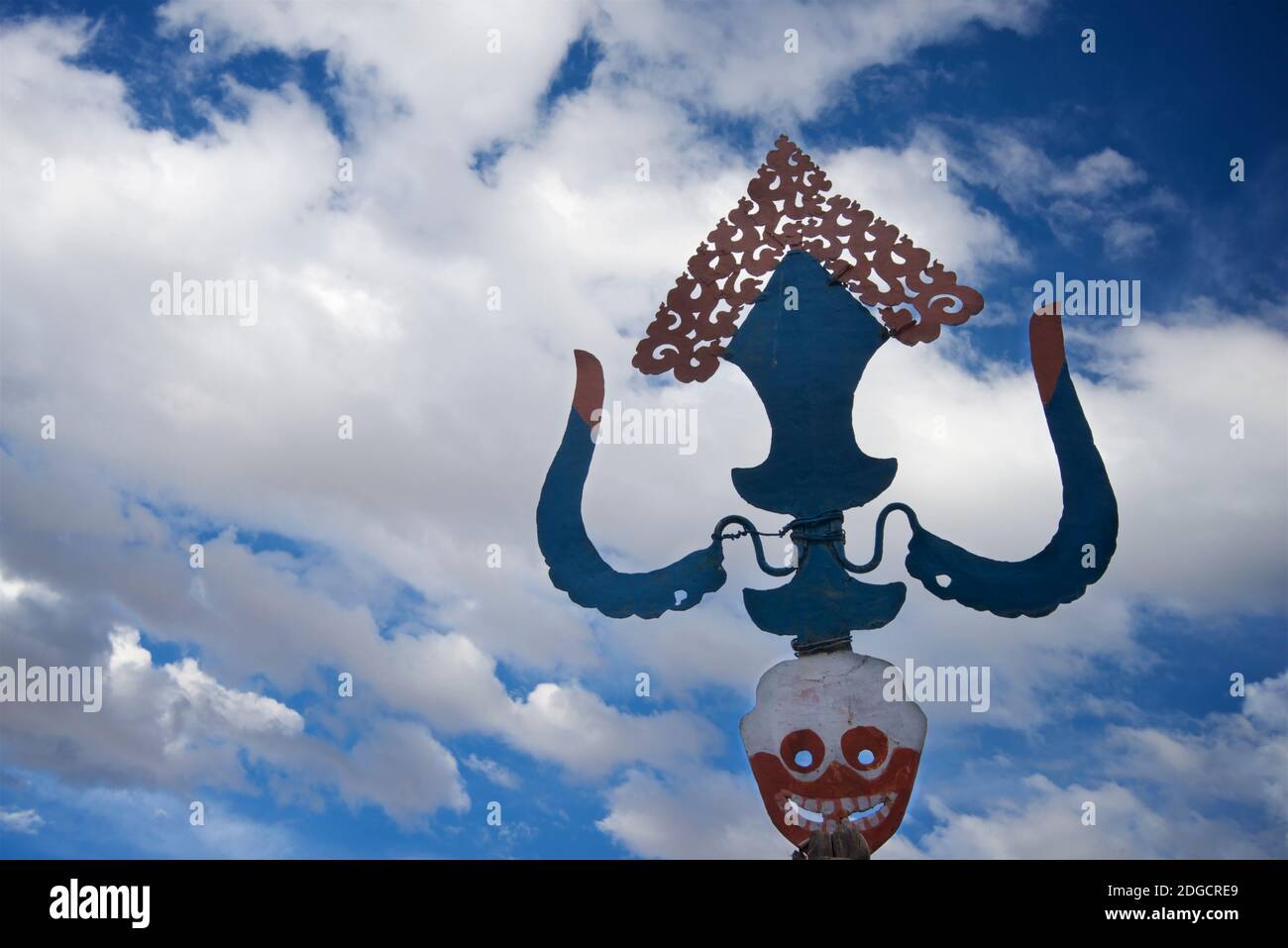 Dettaglio della cima di una ruota di prateria buddista tibetana sul tetto. La parte superiore è progettata per catturare il vento in modo da ruotare il tamburo inferiore. Monastero di Hemis, Hemis, Ladakh, Jammu e Kashmir, India. Iconografia buddista compreso il cranio. Foto Stock