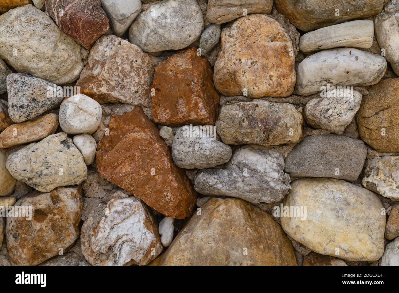 Motivo di pietra irregolare ciottolato grigio e marrone accatastato in sfondo parete Foto Stock