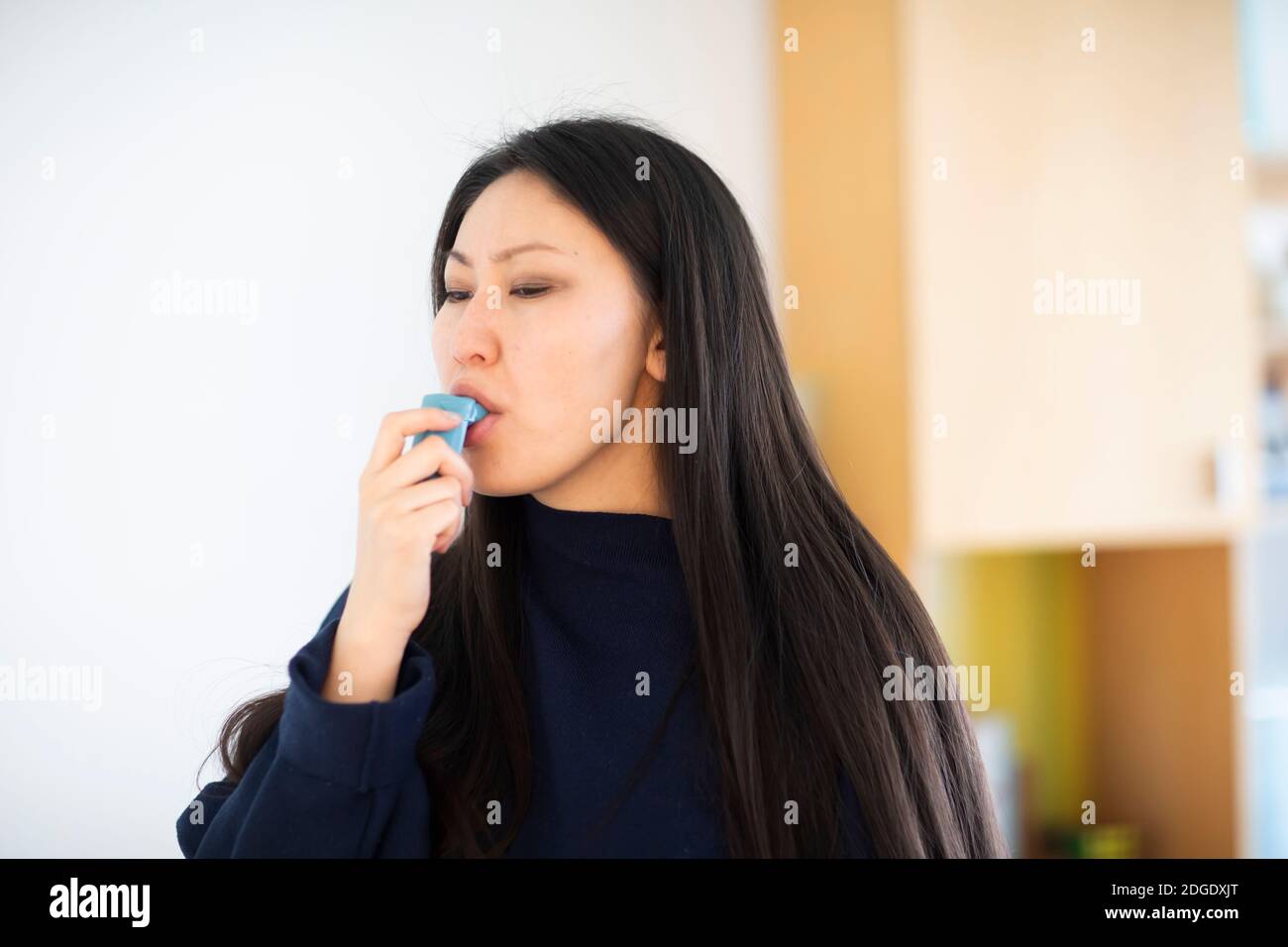 giovane donna asia femmina con capelli lunghi con spray asma Foto Stock