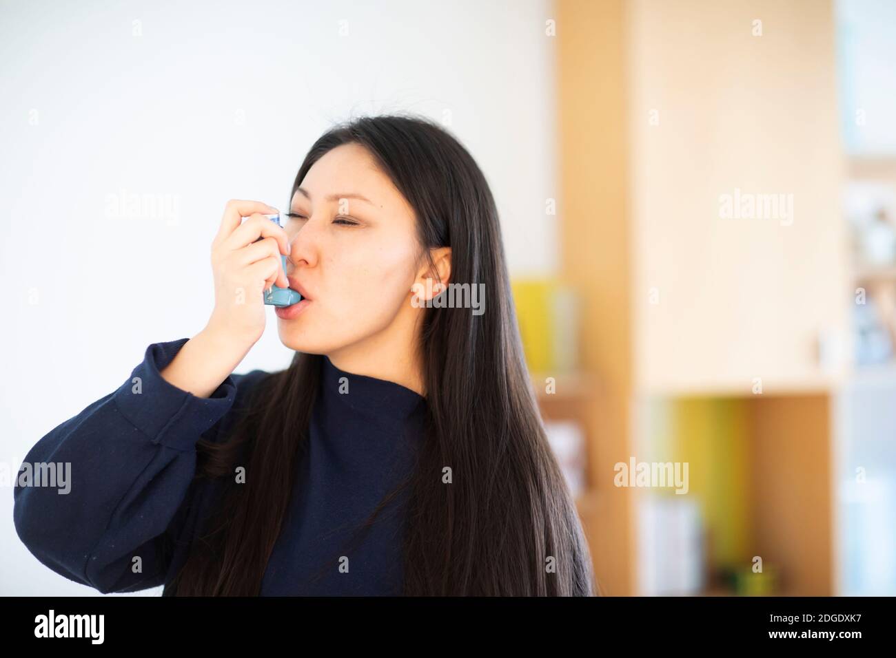giovane donna asia femmina con capelli lunghi con spray asma Foto Stock