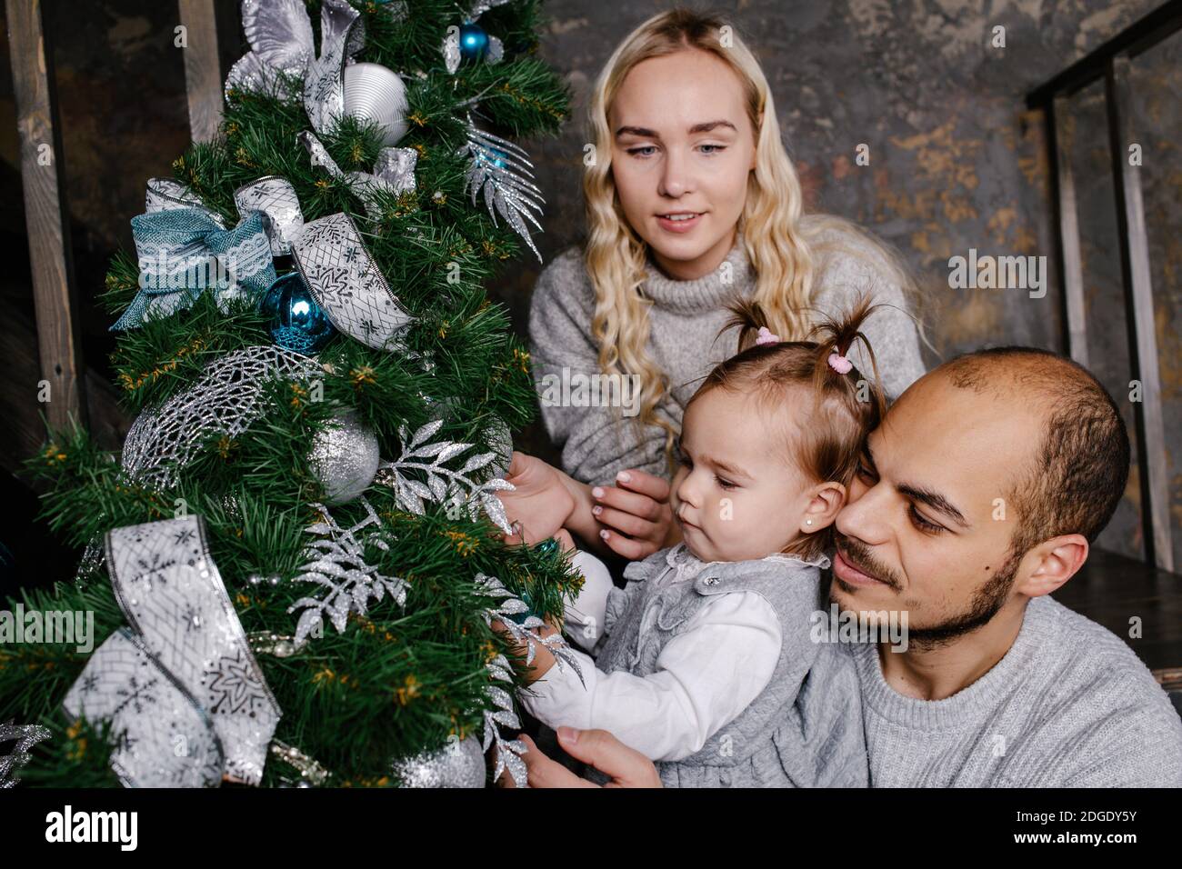 Felice famiglia decorare albero artificiale natale a casa insieme. Foto Stock