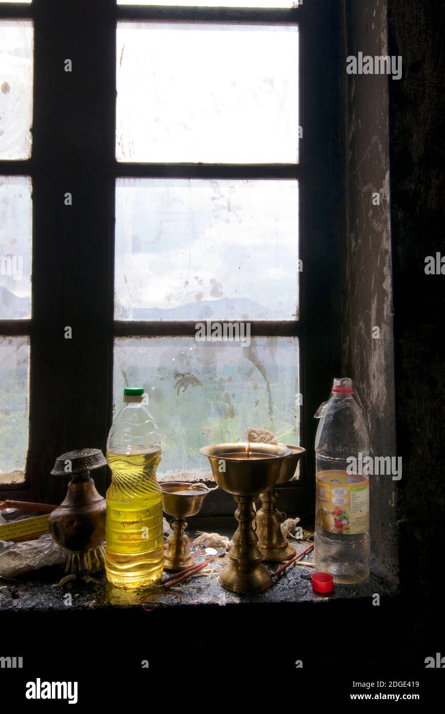 Candele votive rituali illuminate e bottiglie d'olio retroilluminate in una finestra, Royal Shey Palace, Shey, Ladakh, Jammu e Kashmir, India Foto Stock