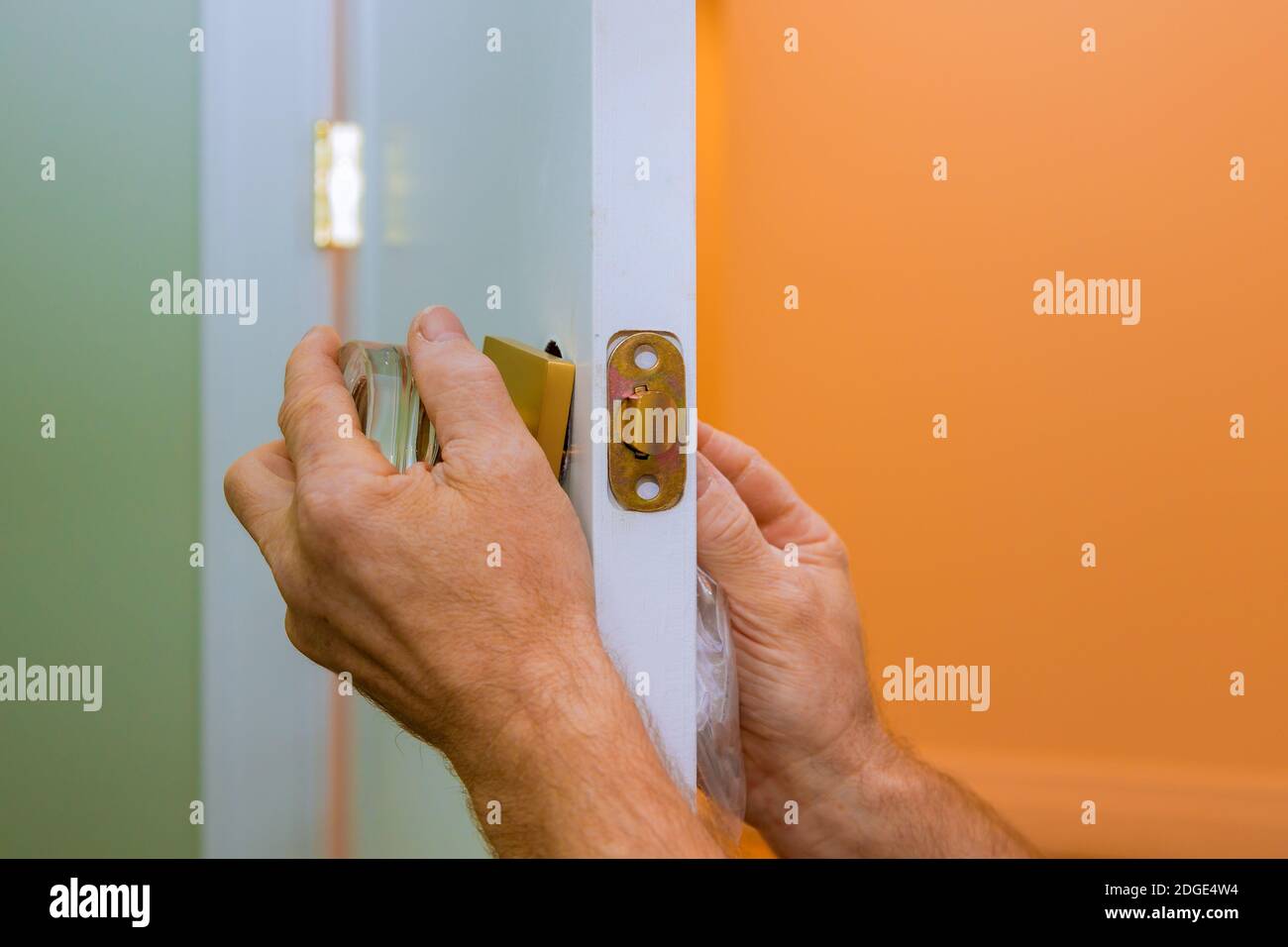 L'operatore ripara la serratura della portiera nelle mani del lavoratore installando una nuova armadietto della porta Foto Stock